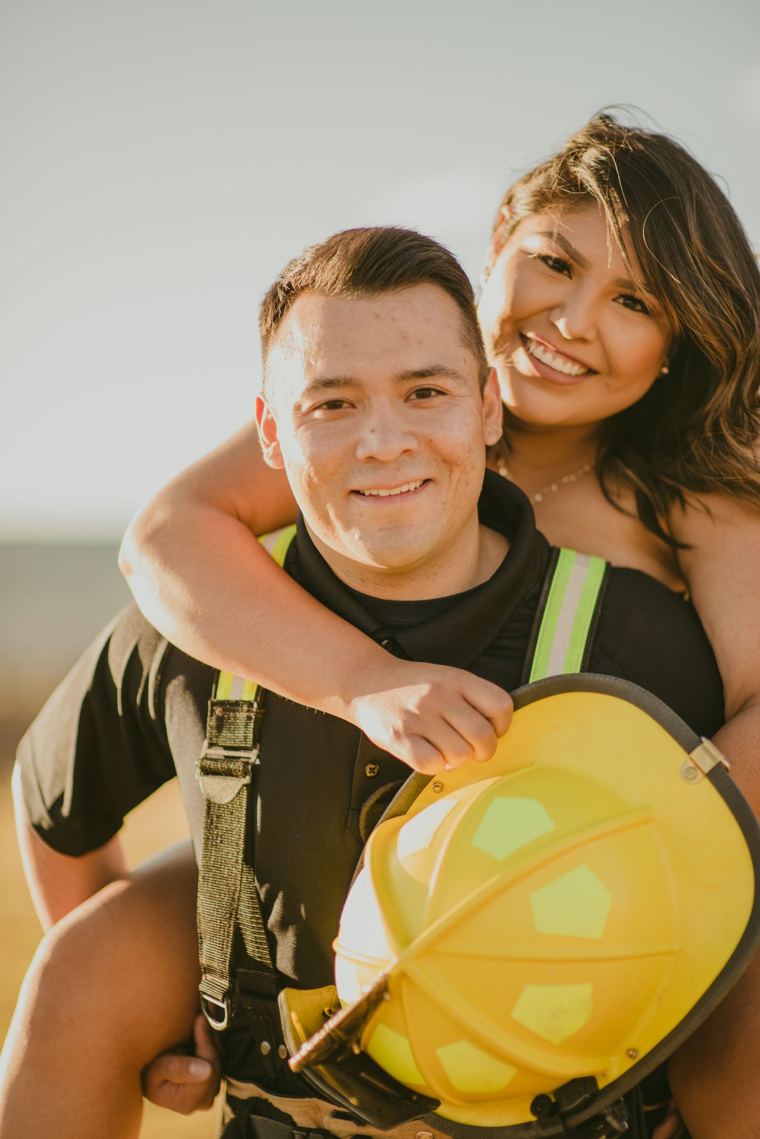 A tender couple sharing intimate moments against a bright sky at sunset.