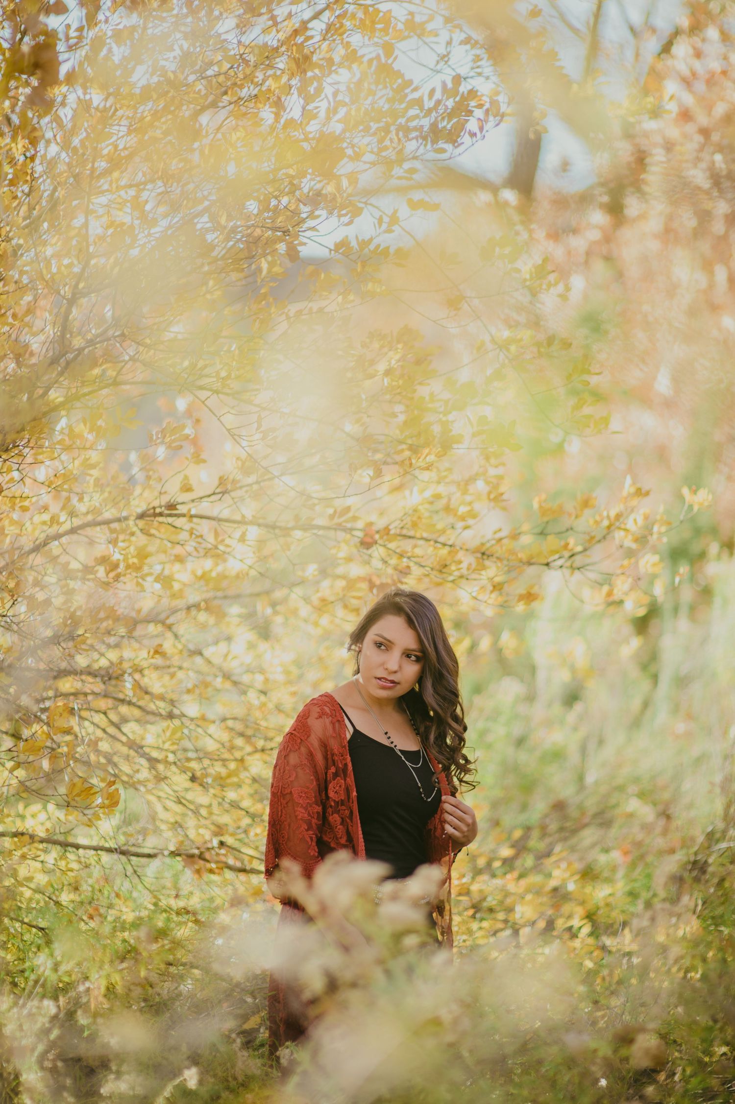Artistic autumn portrait with golden yellow leaves and branches creating a dreamy natural frame.