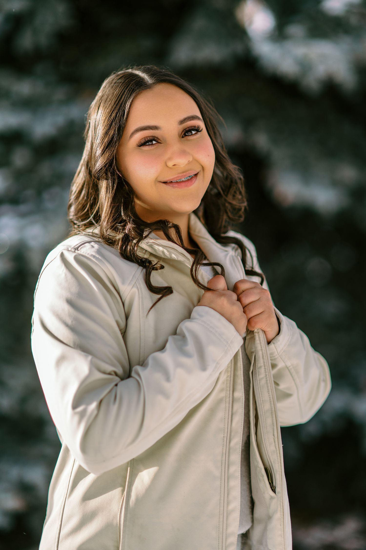 A person wearing a cream-colored winter coat poses playfully against a dark background in a photo series.