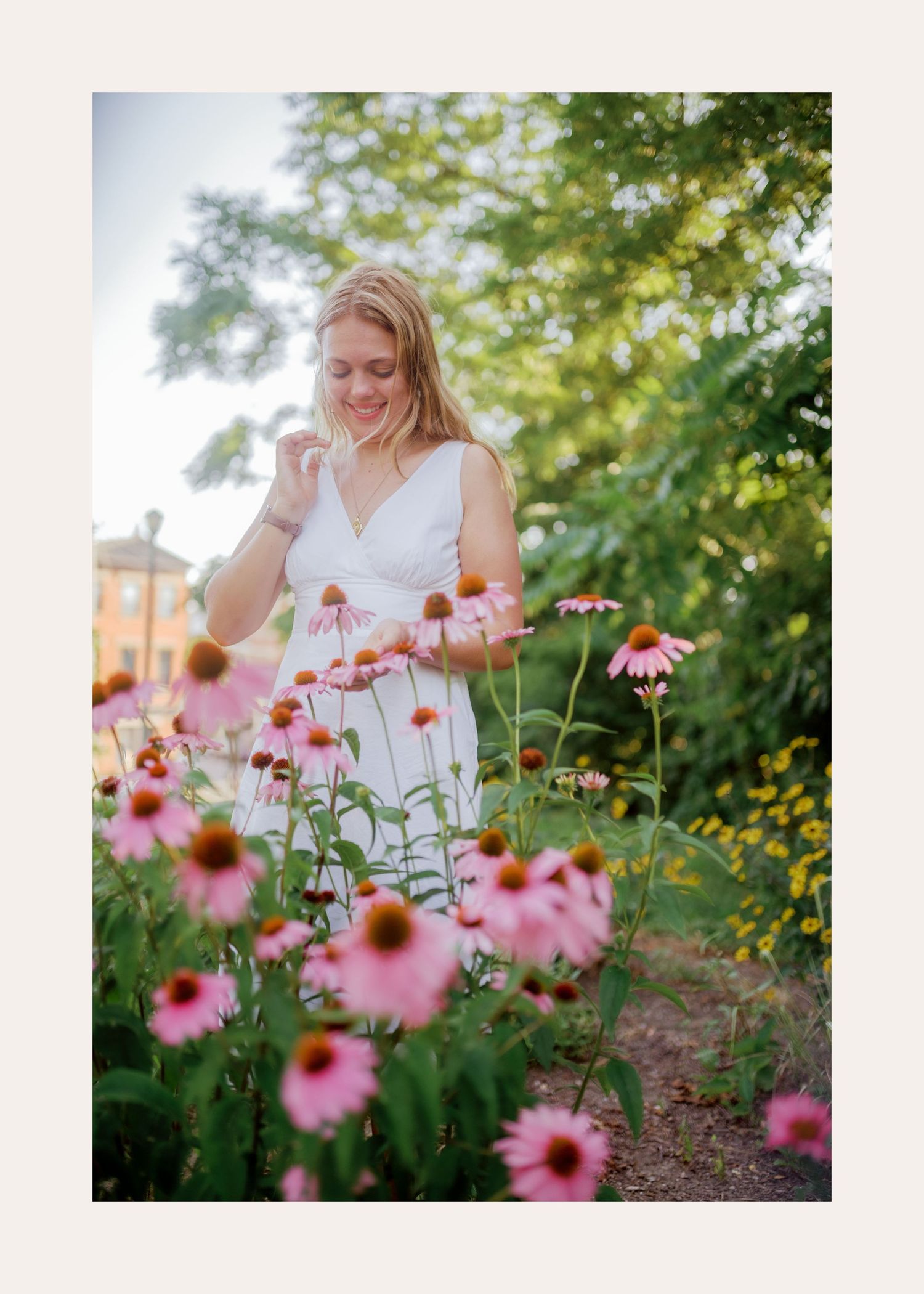 Someone in a white dress stands among pink coneflowers in a summer garden with soft sunlight filtering through trees.