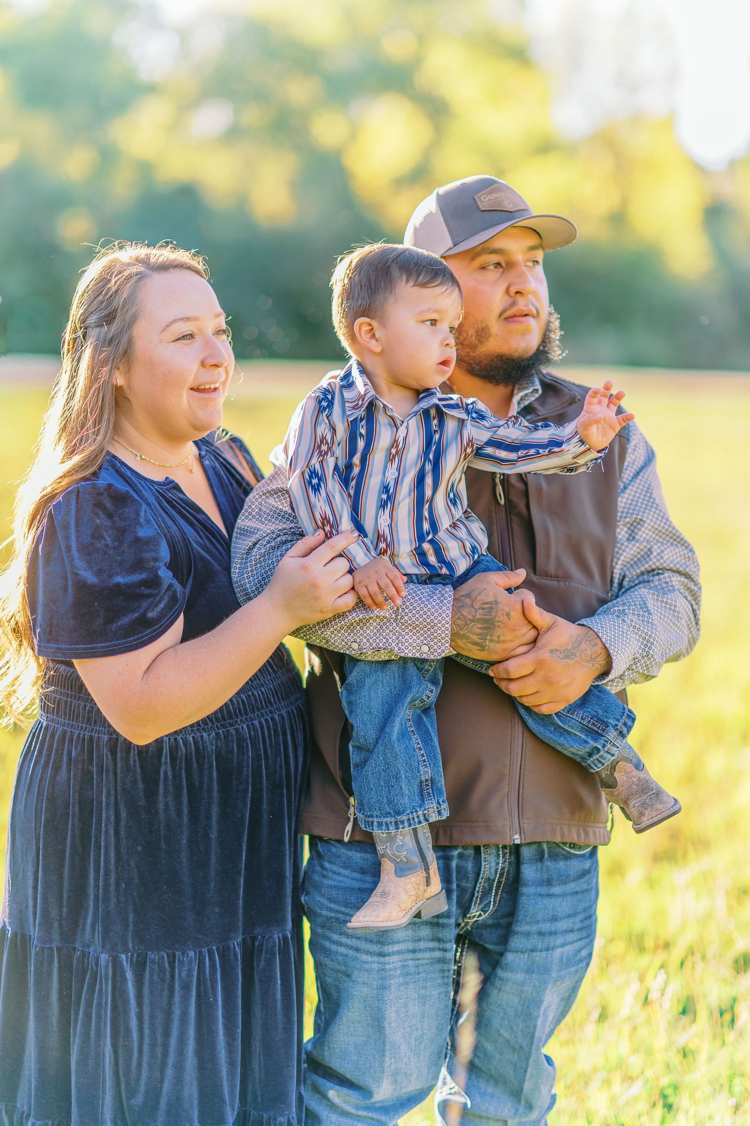 A family shares tender moments together in a sunlit field during golden hour.