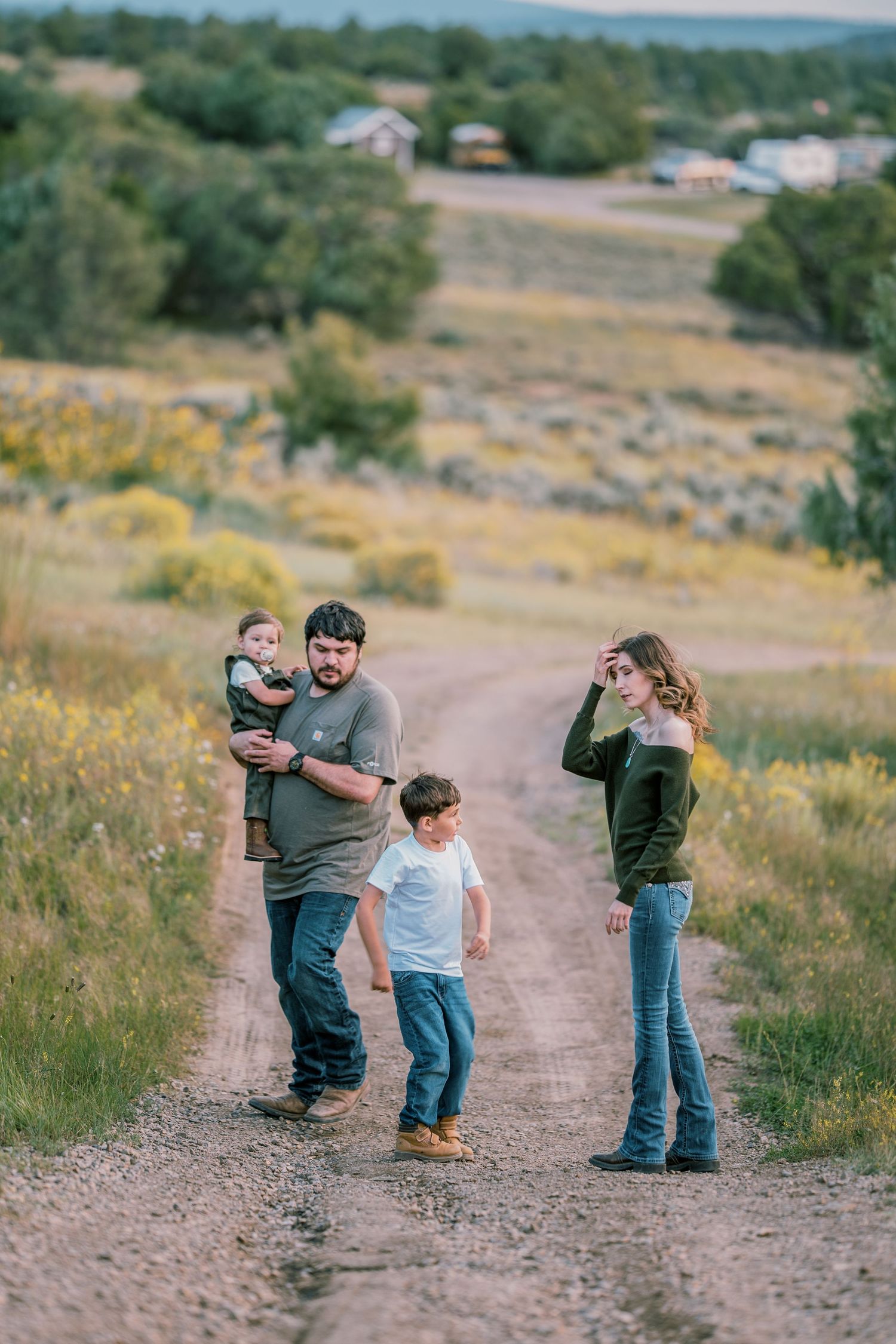 Family enjoying playful moments together on a dirt path surrounded by nature.
