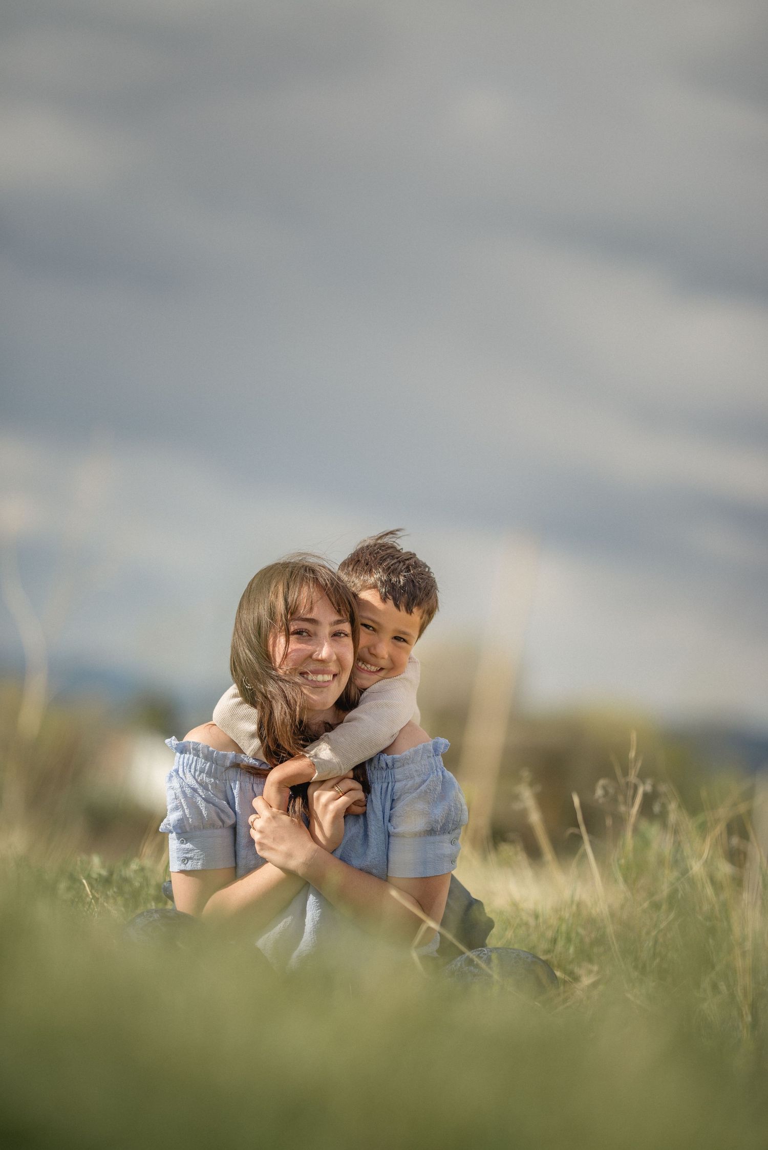 Candid photo of mom and toddler sitting on lush green grass — gentle storytelling by The Amoras.
