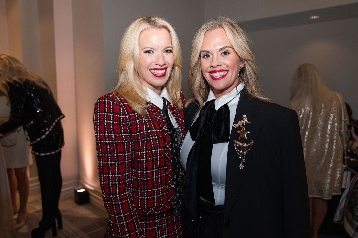 woman wearing a red, black and white checker blazer with a black tie, woman wearing a black blazer with a white blouse
