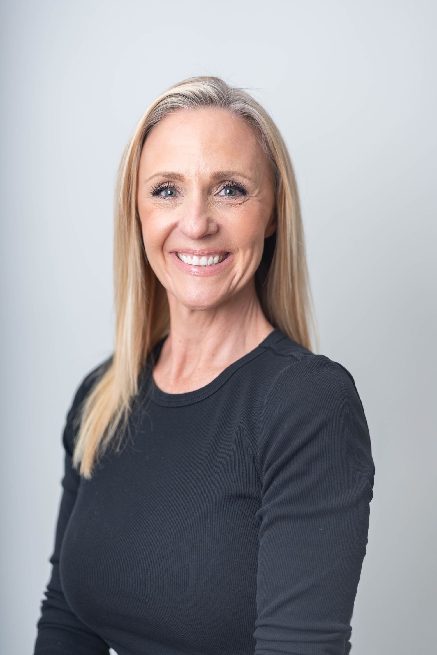 woman smiling and wearing a black long sleeved blouse