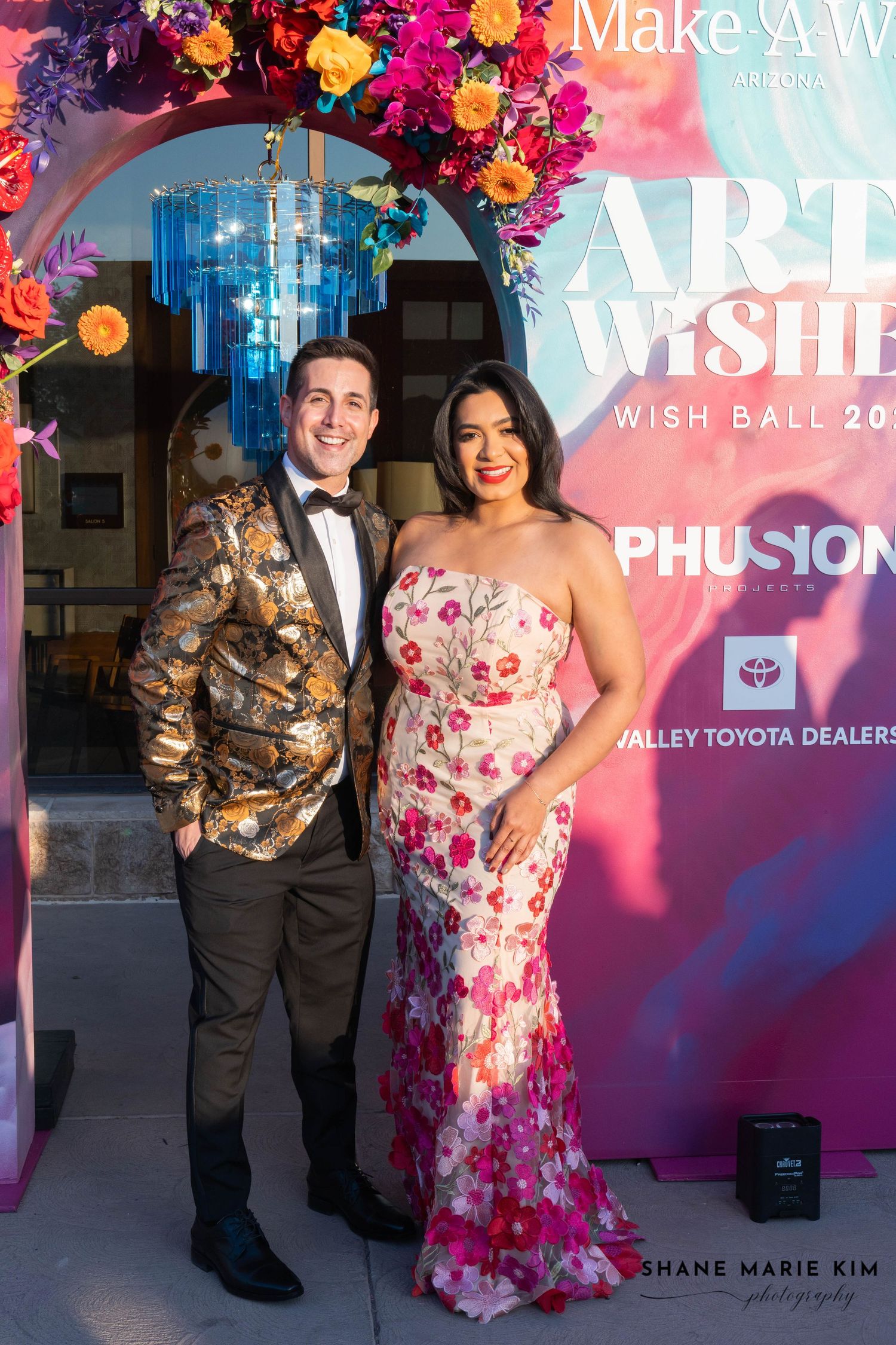 man wearing a patterned blazer and woman wearing a tubed floral dress