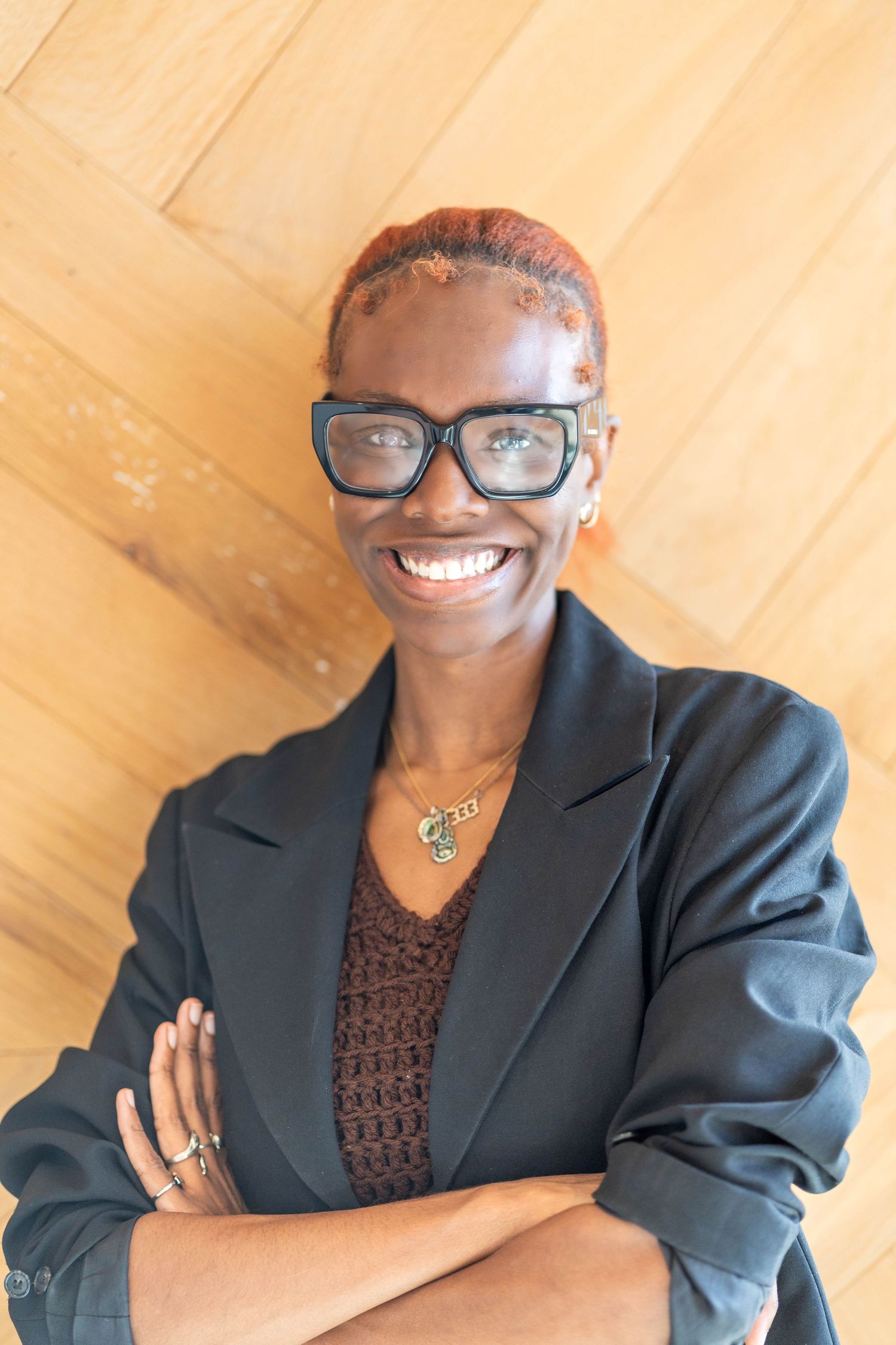 girl with black framed glasses, girl wearing a black blazer, girl folding her arms
