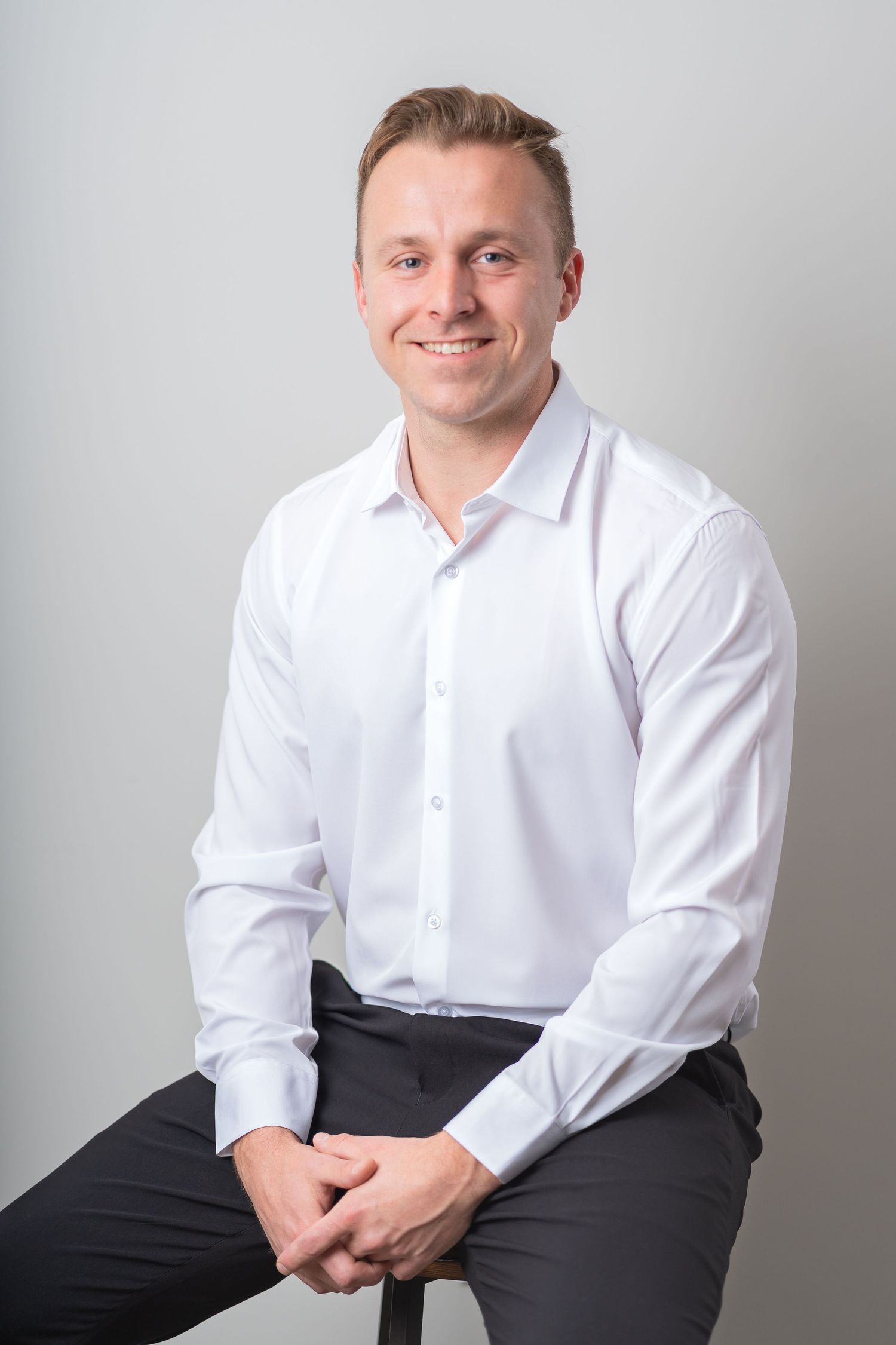 man sitting down, man wearing a long white long sleeved shirt with black pants