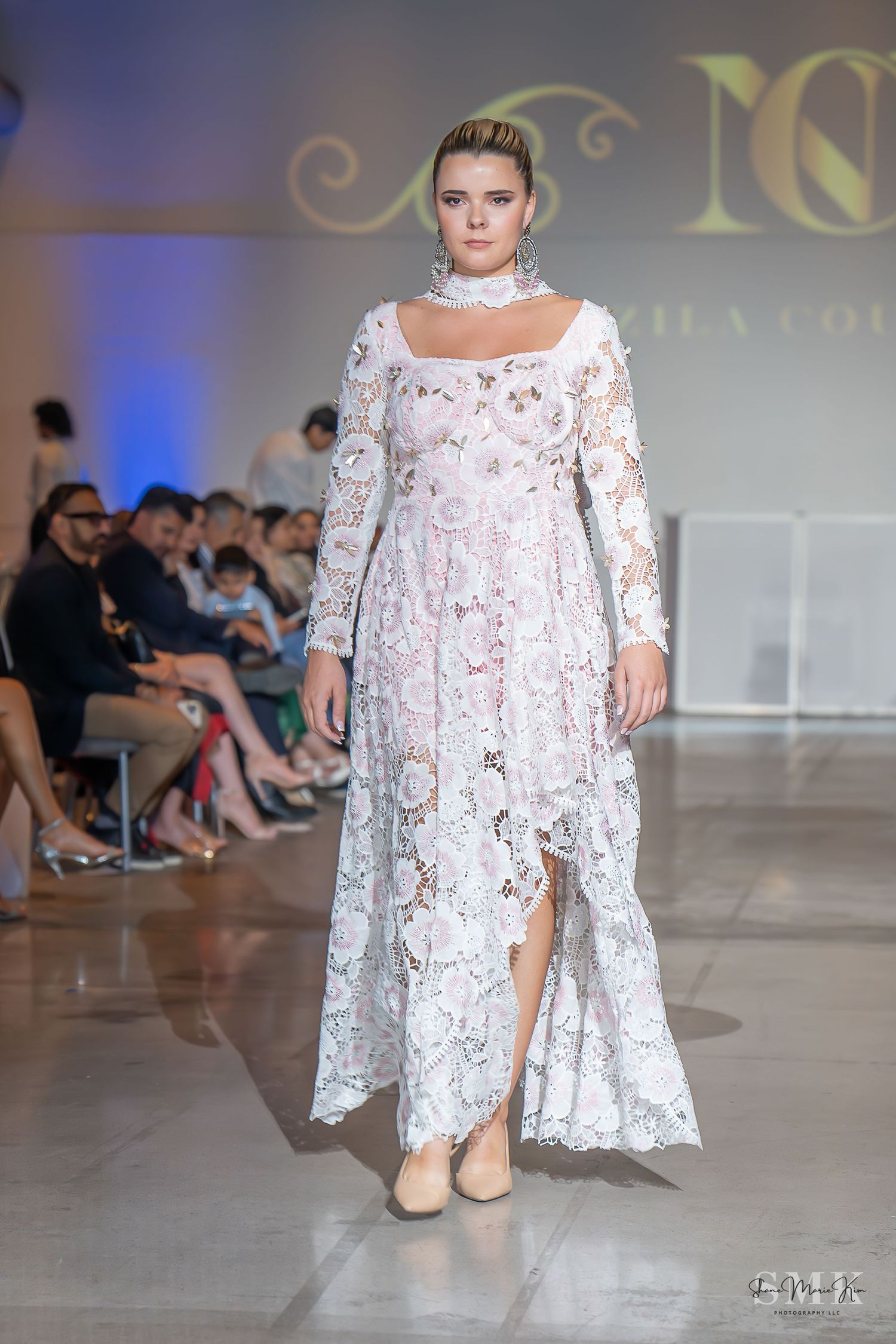 girl wearing a long sleeved laced white dress at a fashion show