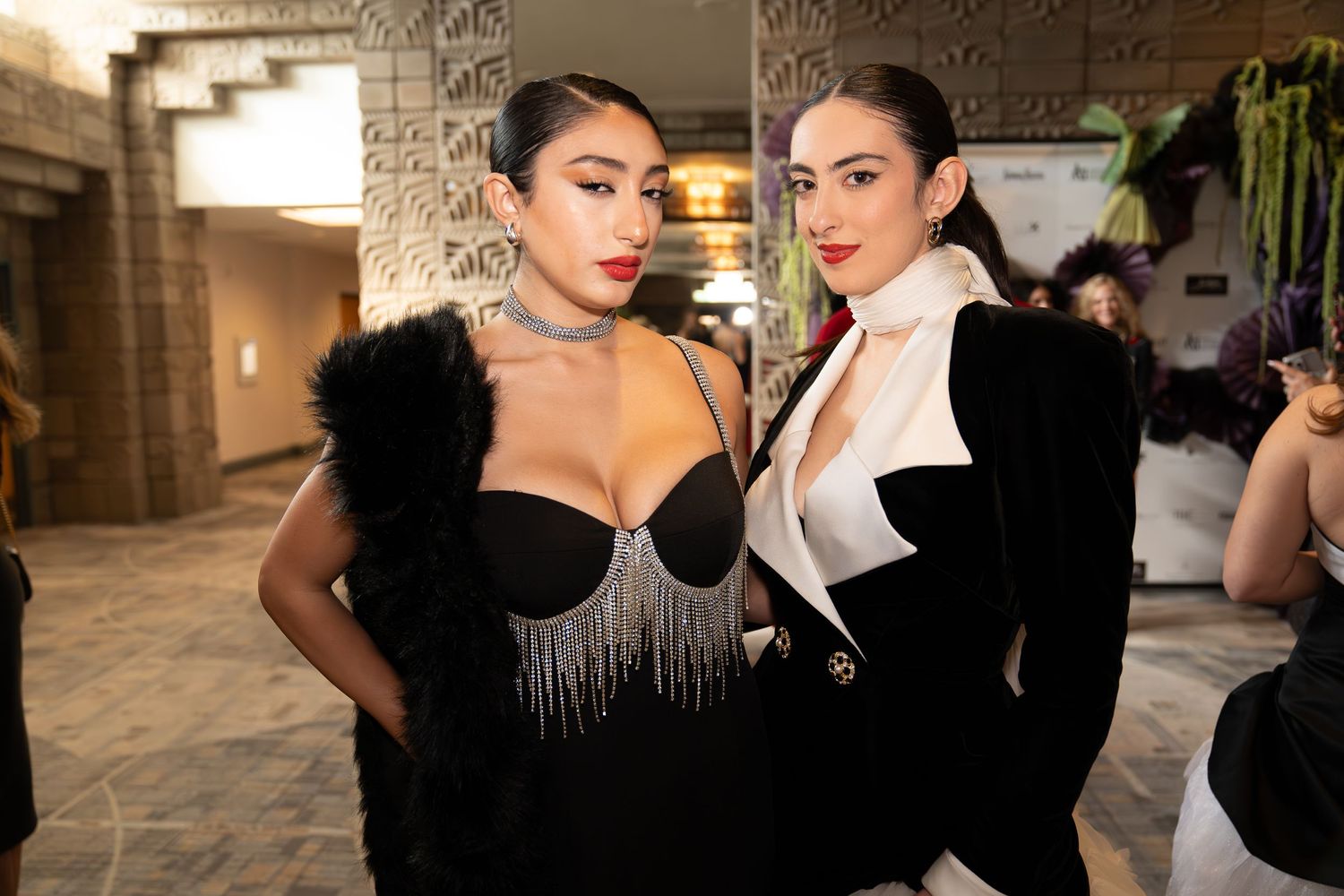girl has a fur scarf on shoulder, wearing a black dress with sequins, woman wearing a black and white pantsuit