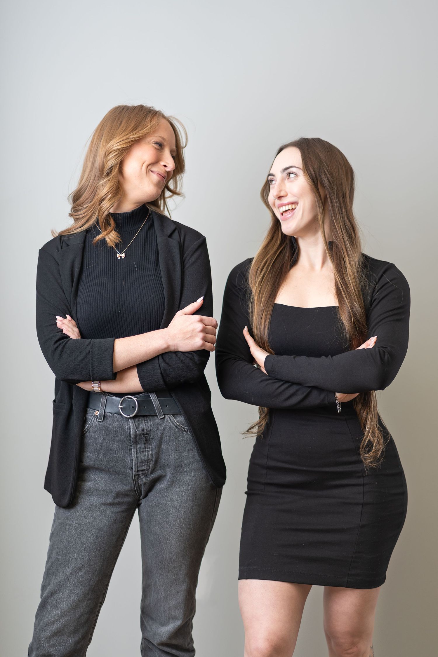 two women smiling at each other, women wearing black and grey