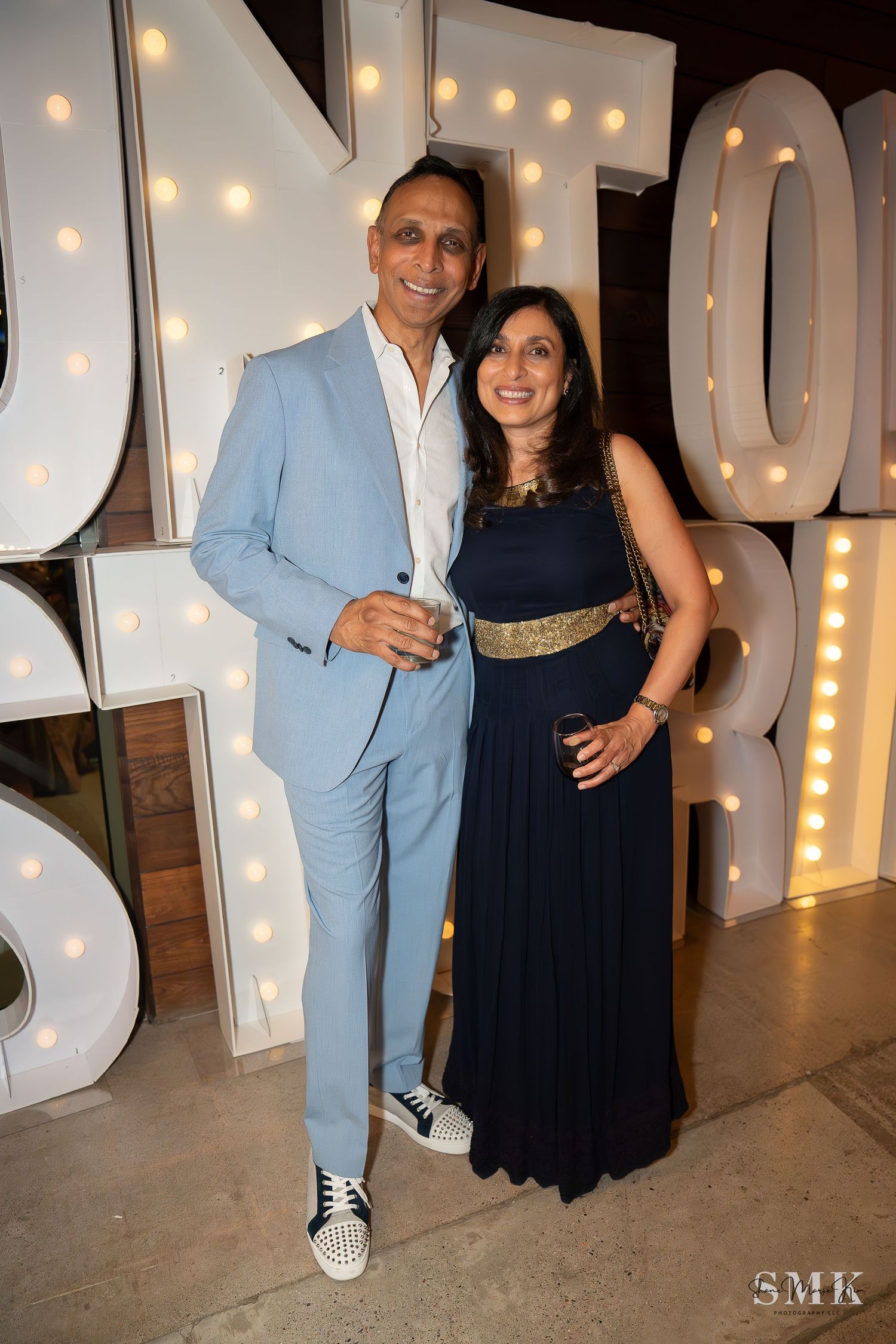 man wearing a blue suit and woman wearing a black dress with a gold belt