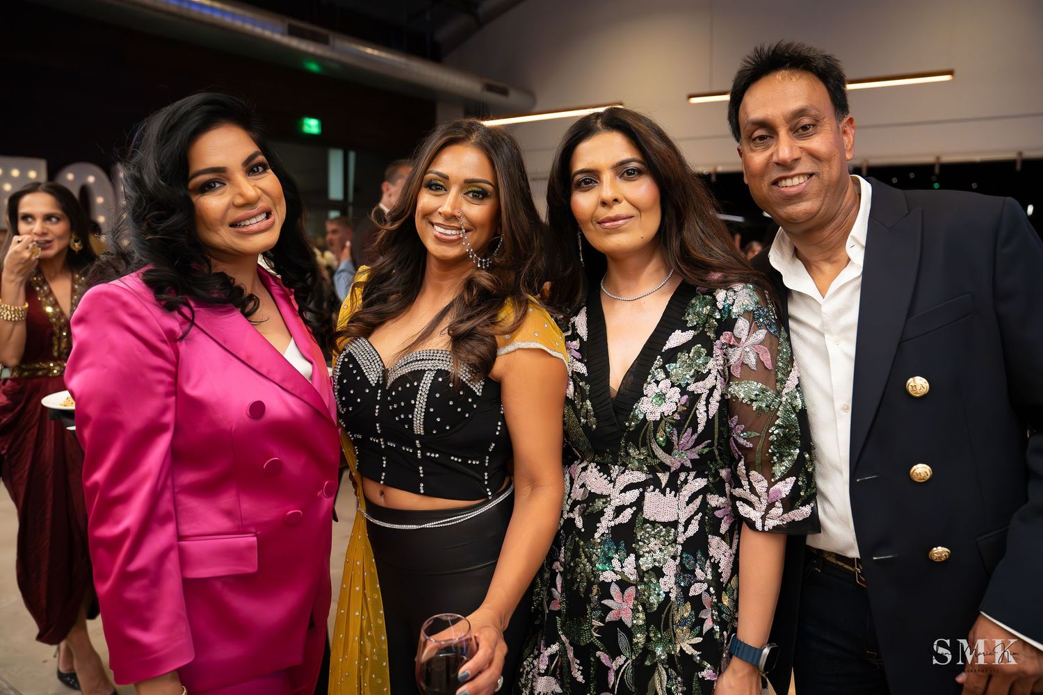 girl with a bright pink blazer, girl with sequined two piece outfit and man wearing a suit