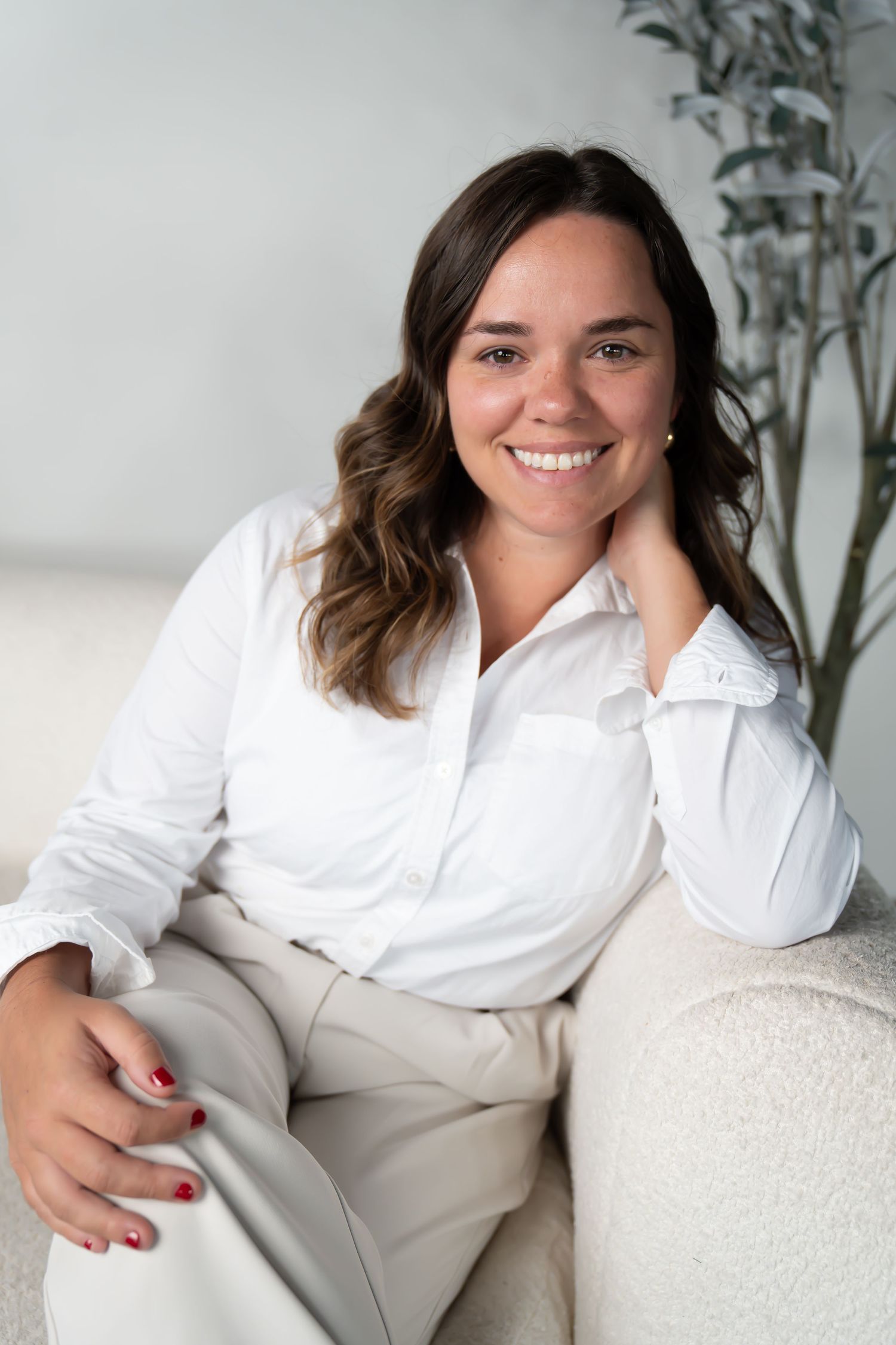 girl wearing a white long sleeve with khaki pants, sitting and smiling