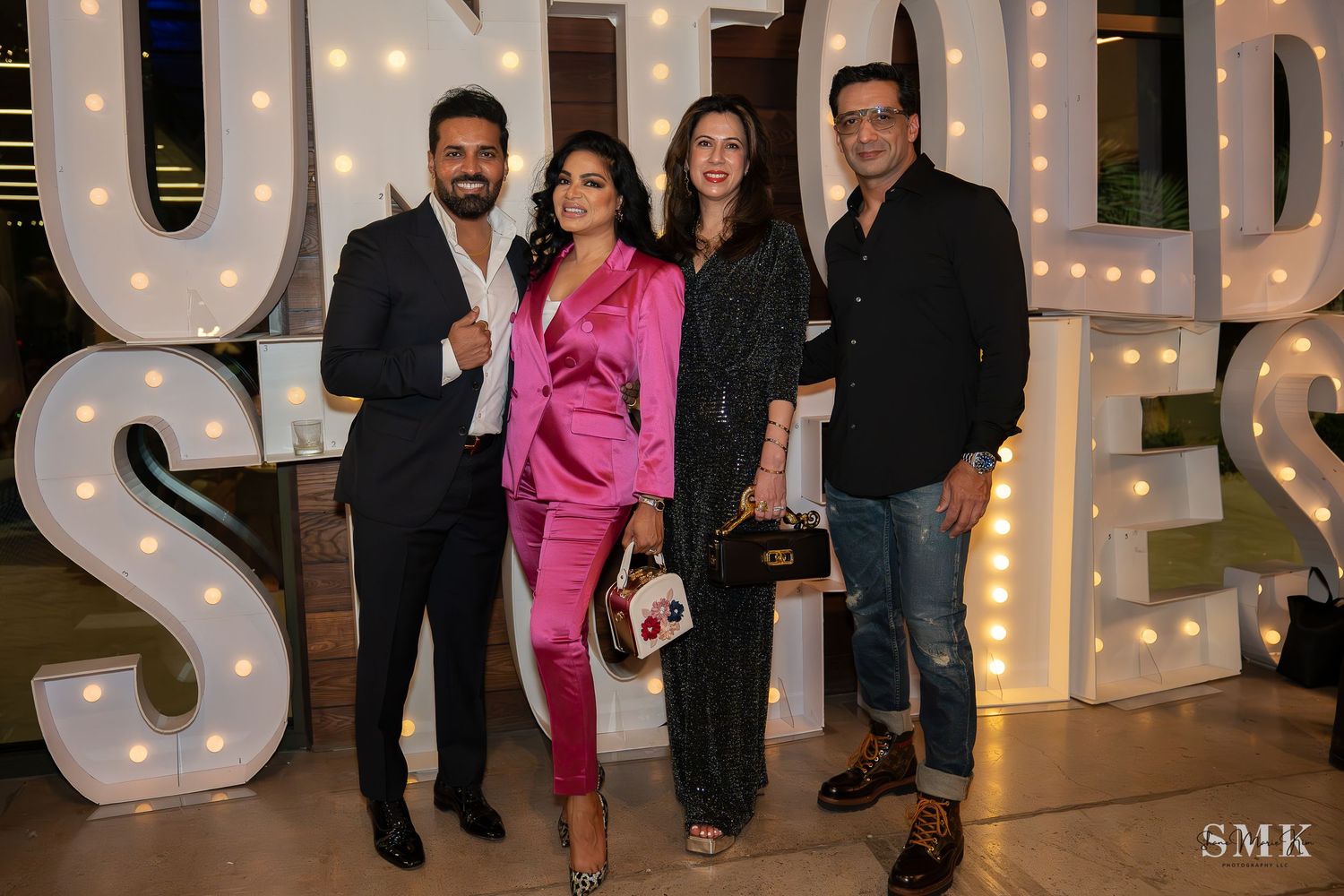 couples posed in business casual outfits, woman wearing a bright pink pant suit