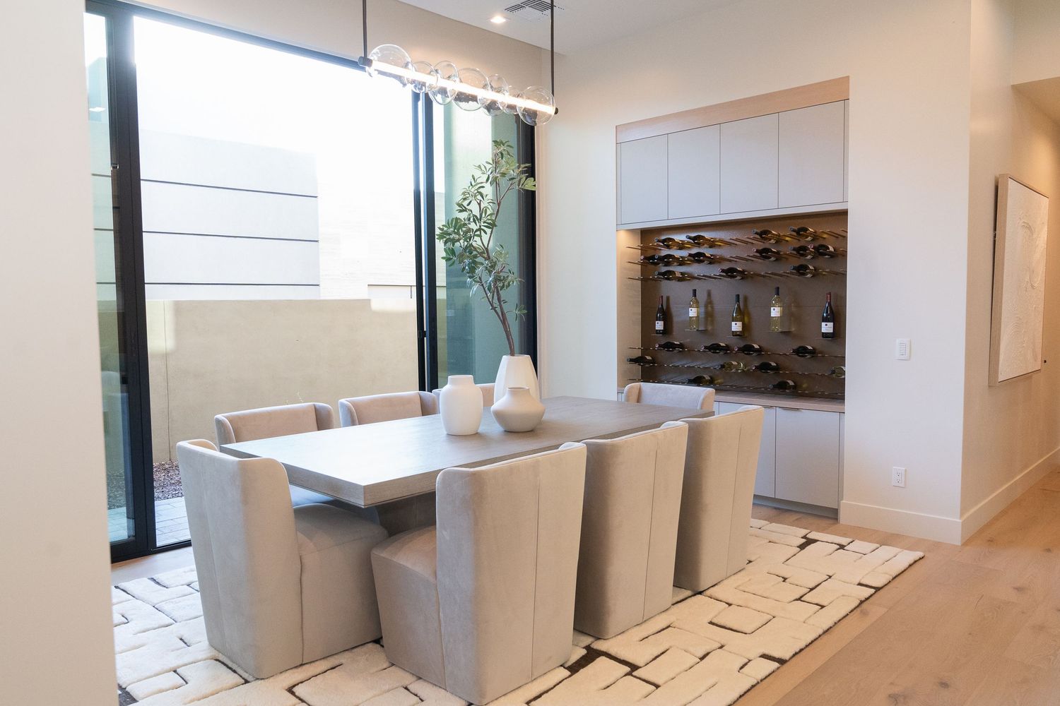 dining area that includes a dining table that seats 8 people, wine shelf and access to outdoor patio