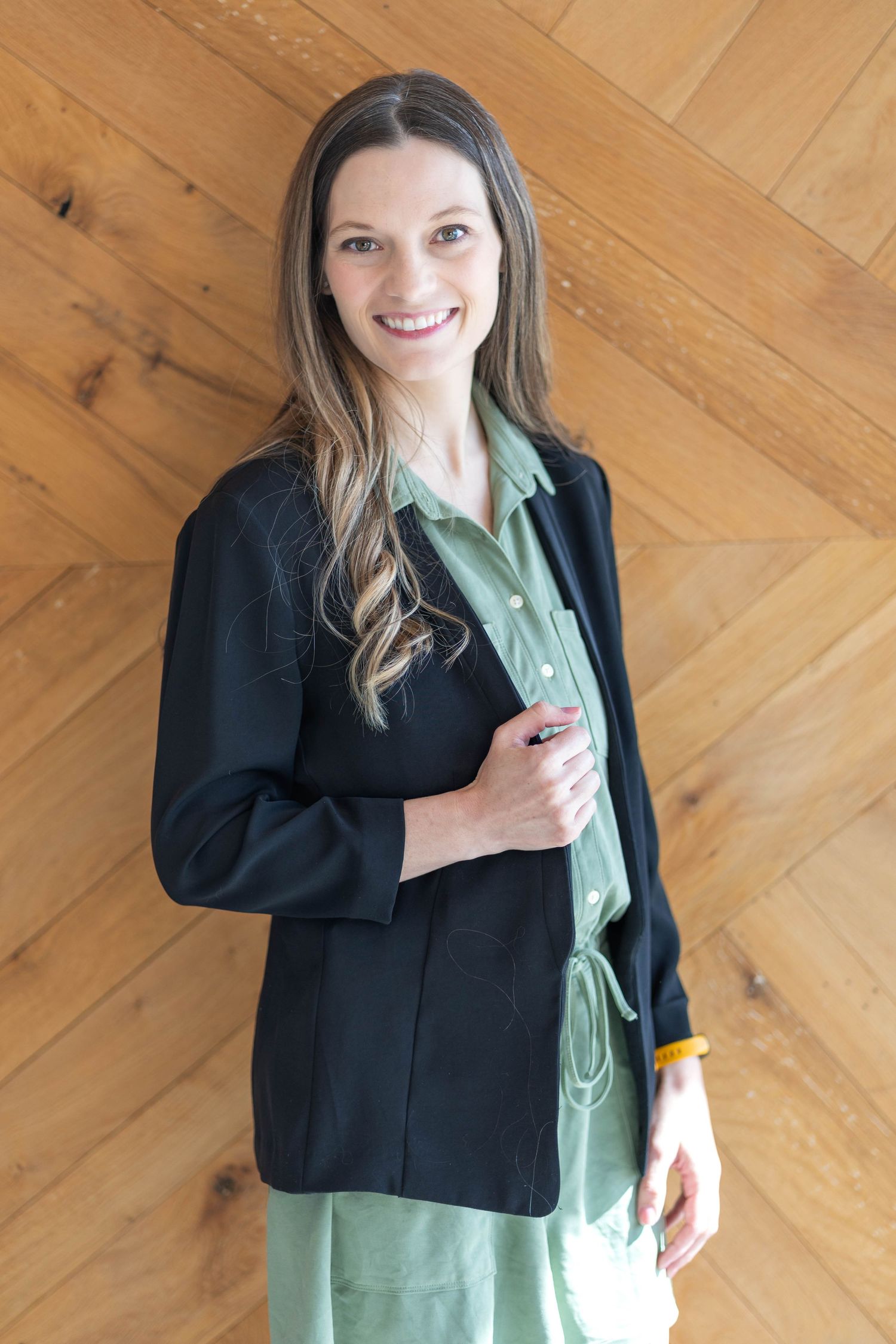 girl wearing a black blazer, girl wearing a light green dress, girl placing hand on blazer