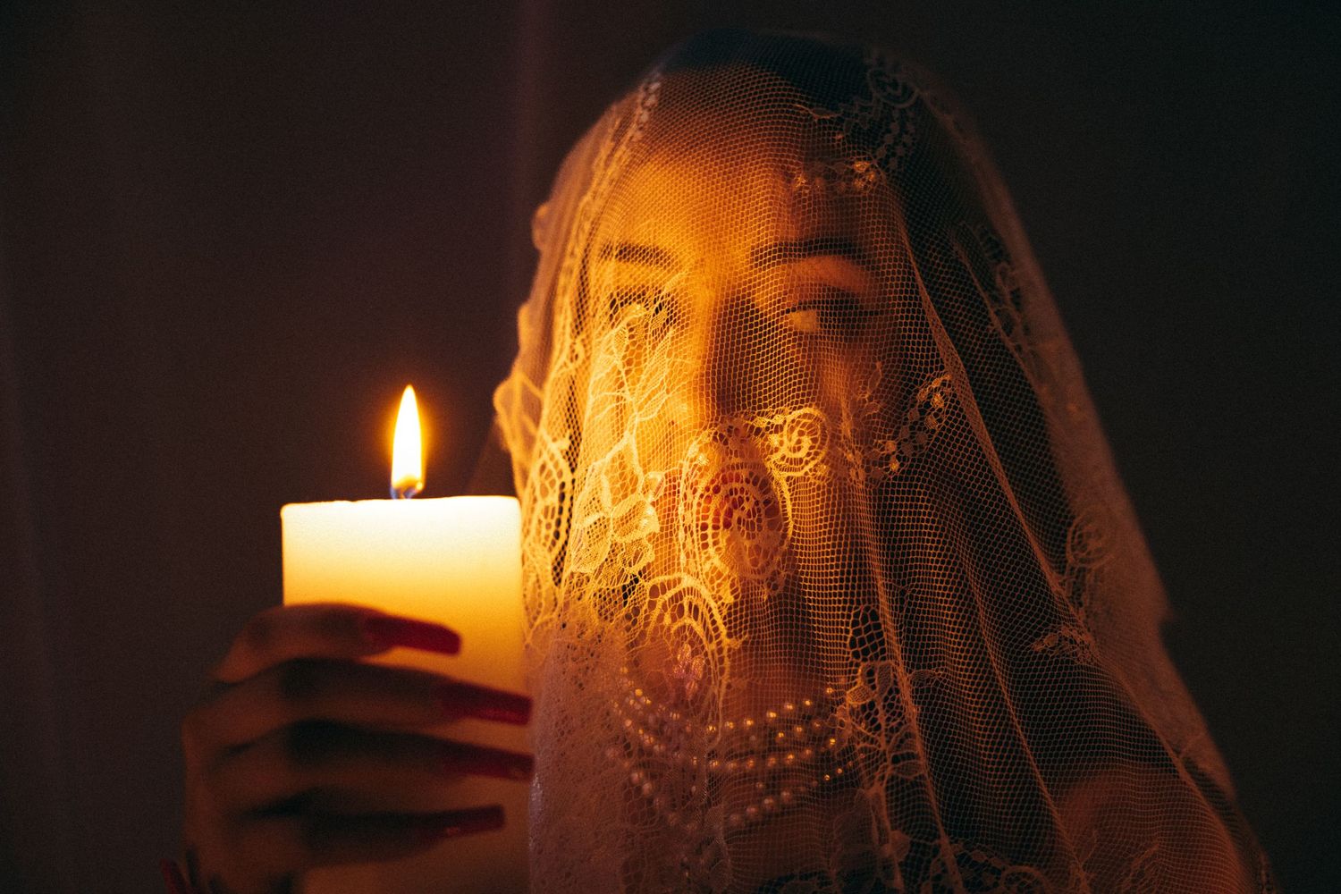 Atmospheric candlelit portrait with veil and warm glowing light.