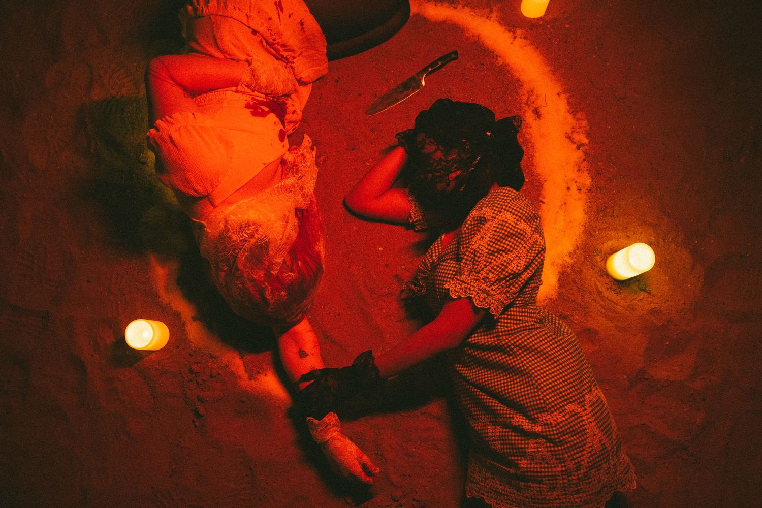 Red-tinted photos of figures illuminated by candlelight on the ground.