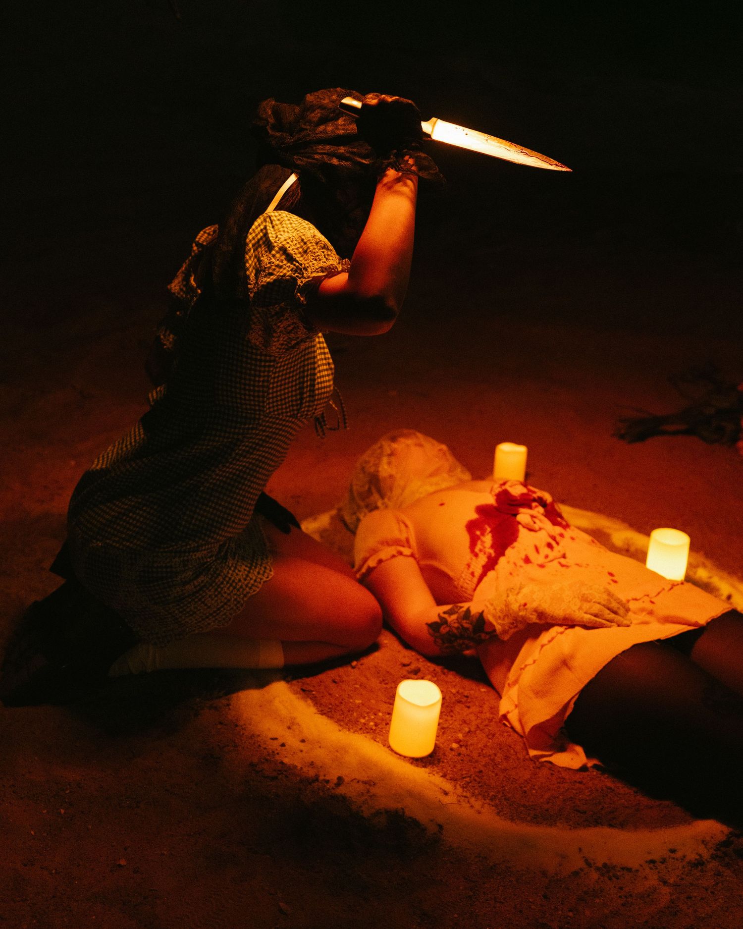 Candlelit scene on the ground with figures in vintage clothing.