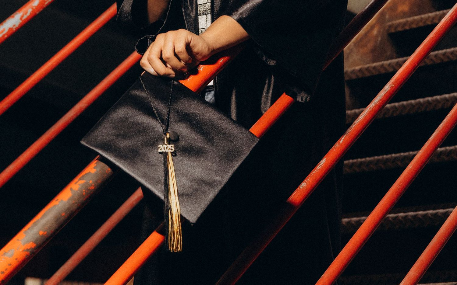 Close-up of hands holding graduation tassels against dark background.
