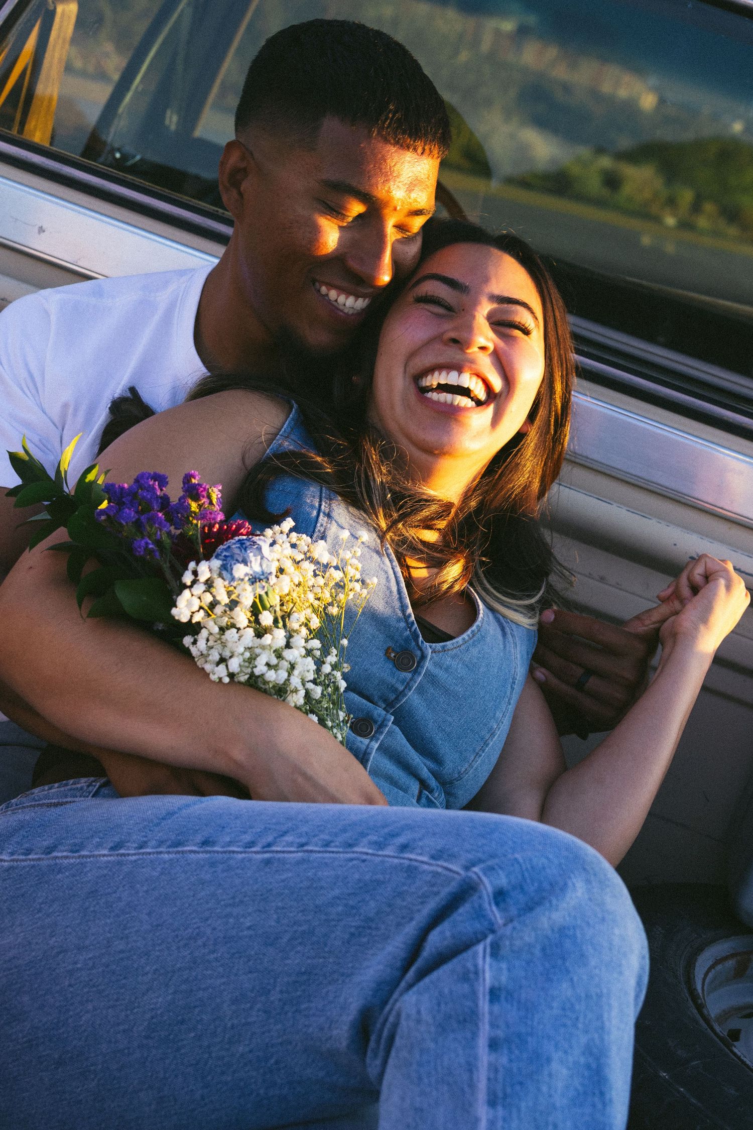 Candid moments of joy captured in a car with denim and wildflowers.