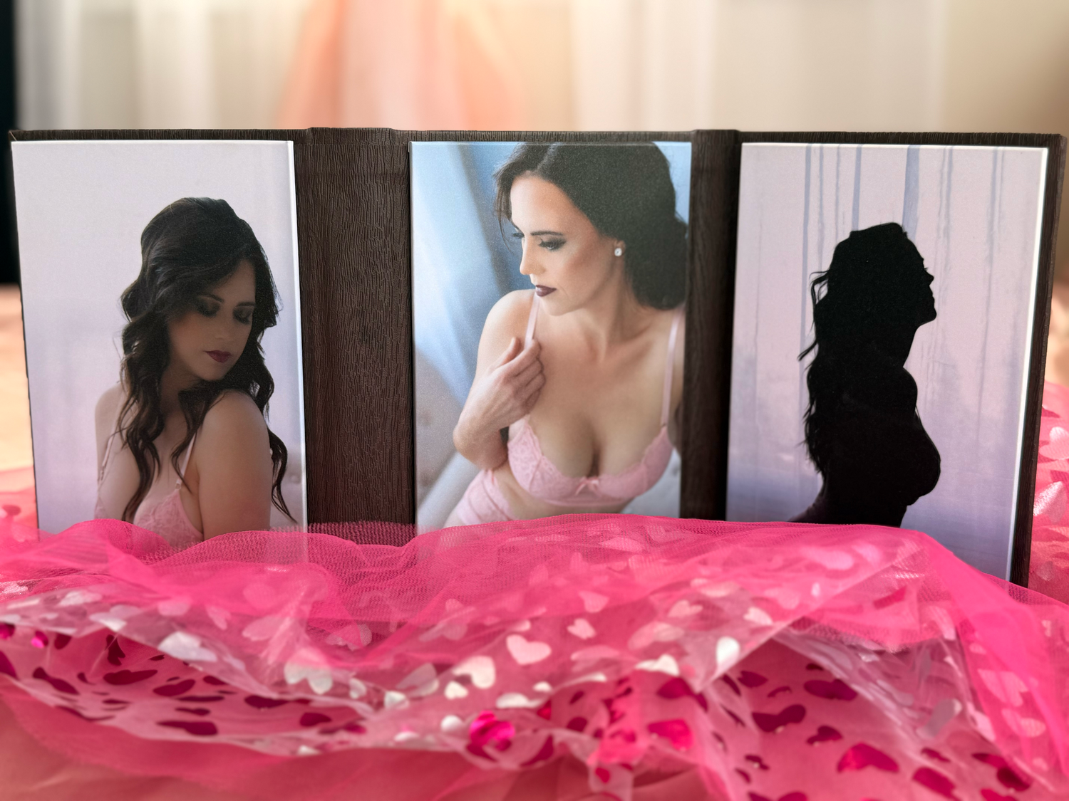 Three portrait photos displayed on black frames with pink tulle fabric draped beneath them.