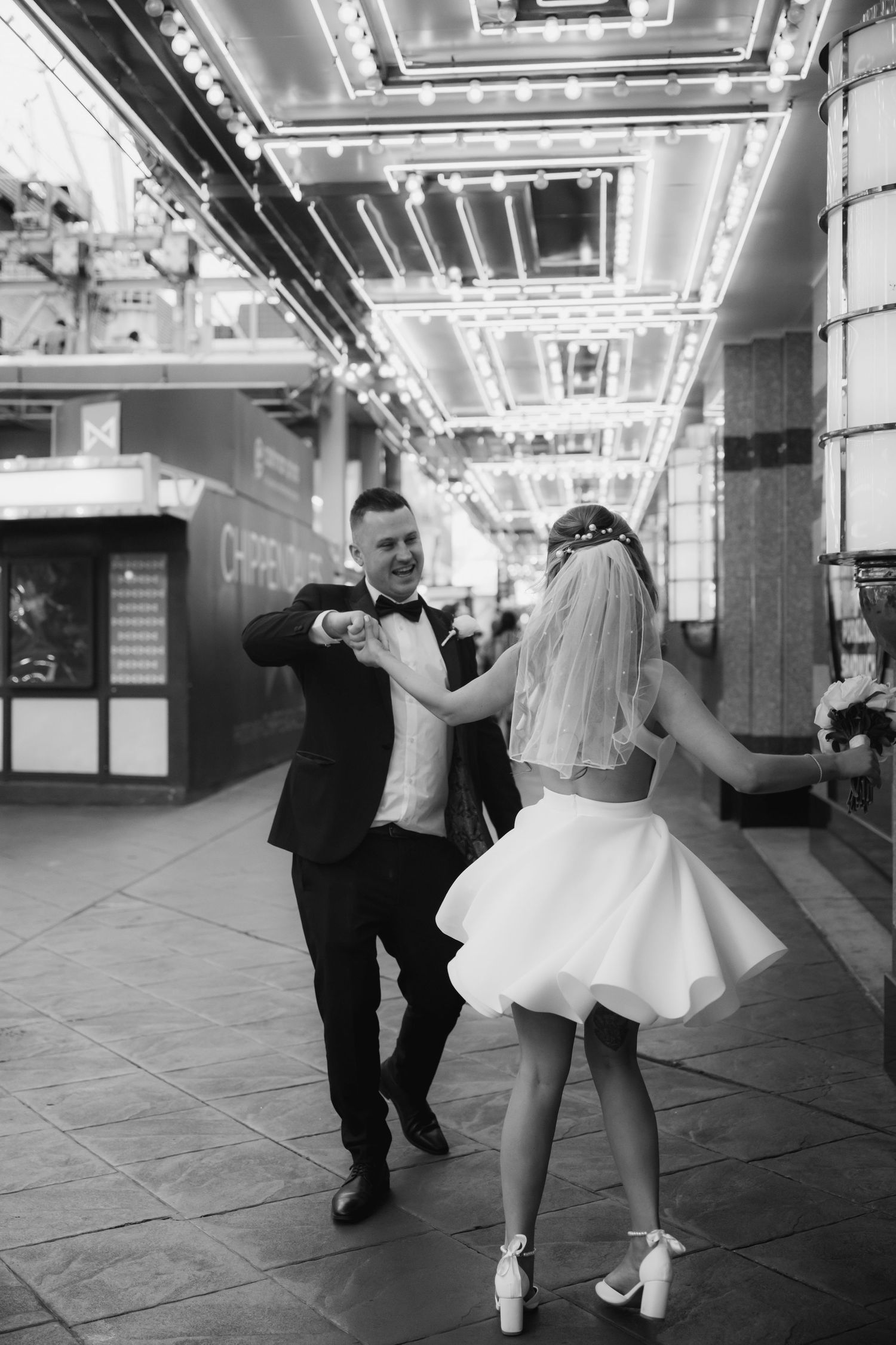 A black and white photo of a couple dancing under illuminated casino ceiling lights.