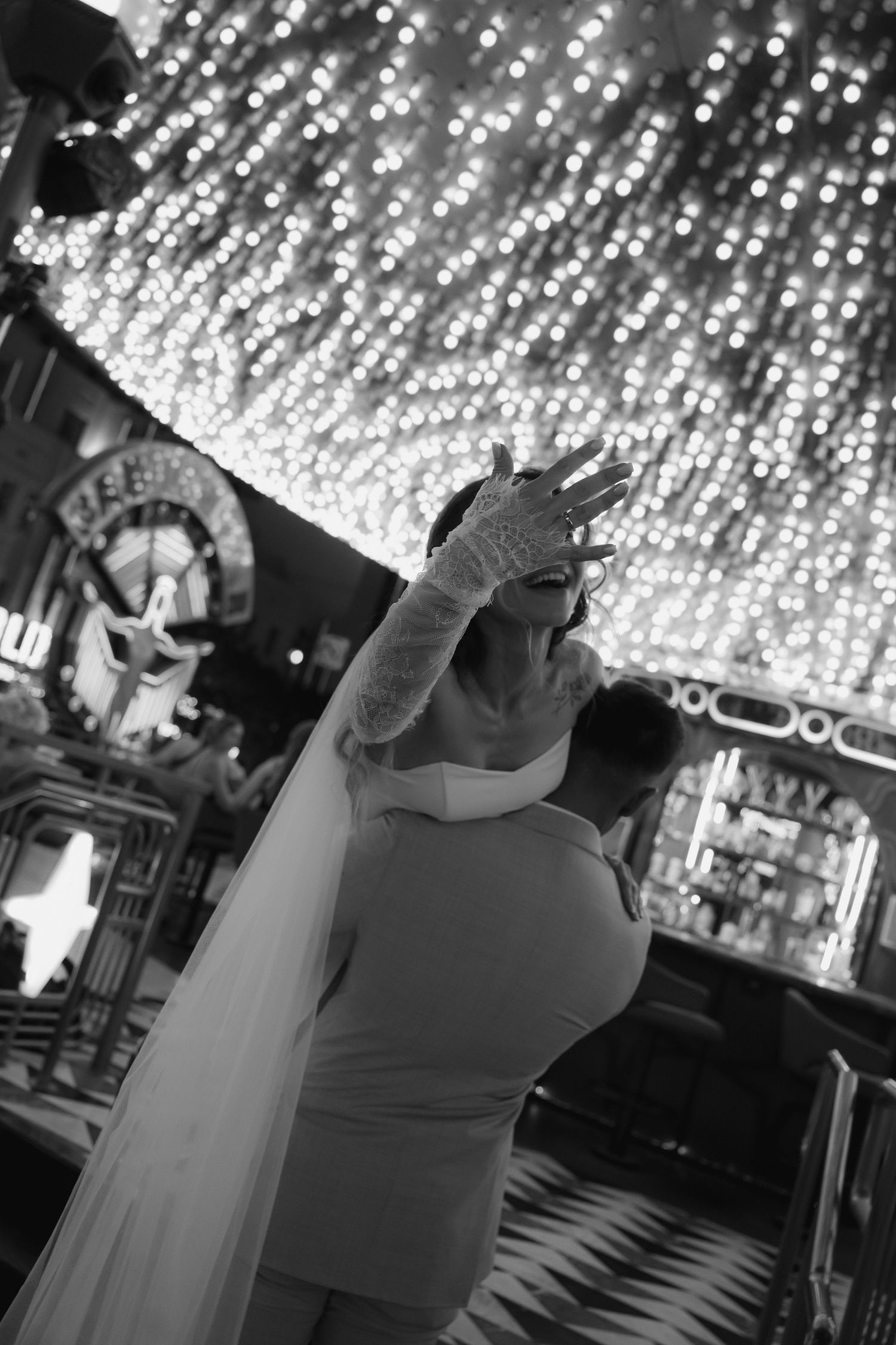 Black and white photo of a bride in a white dress and veil dancing under sparkling lights in Las Vegas.
