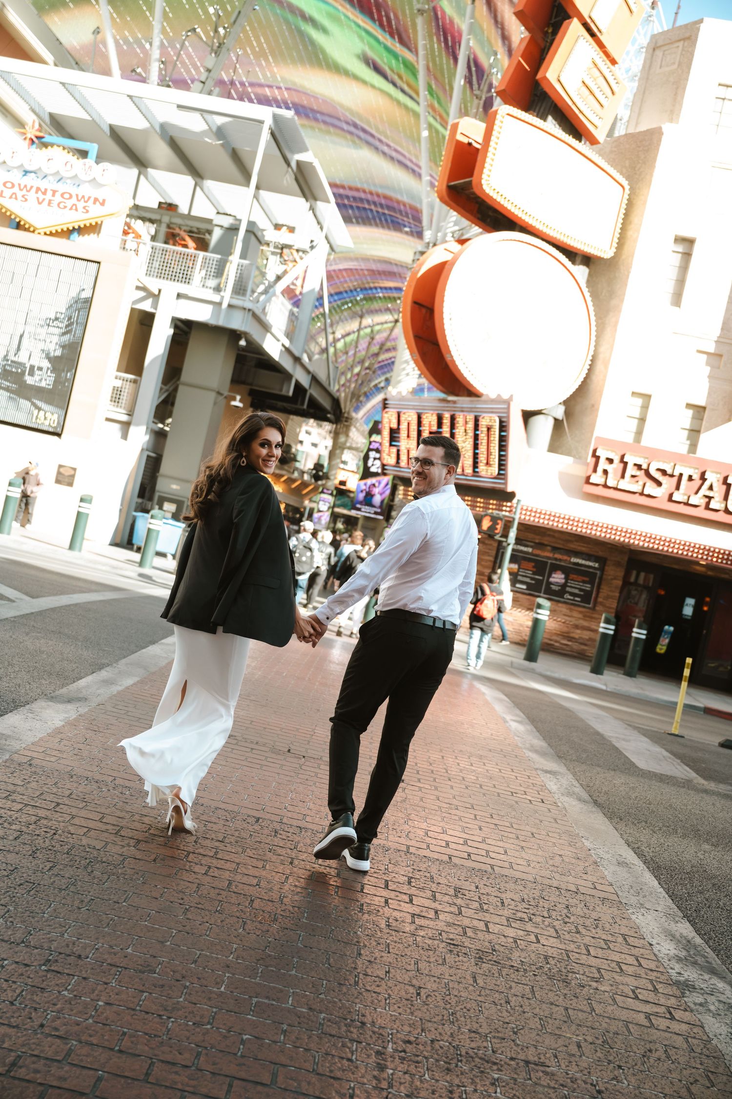 A couple walks hand in hand beneath the bright lights of downtown Las Vegas.