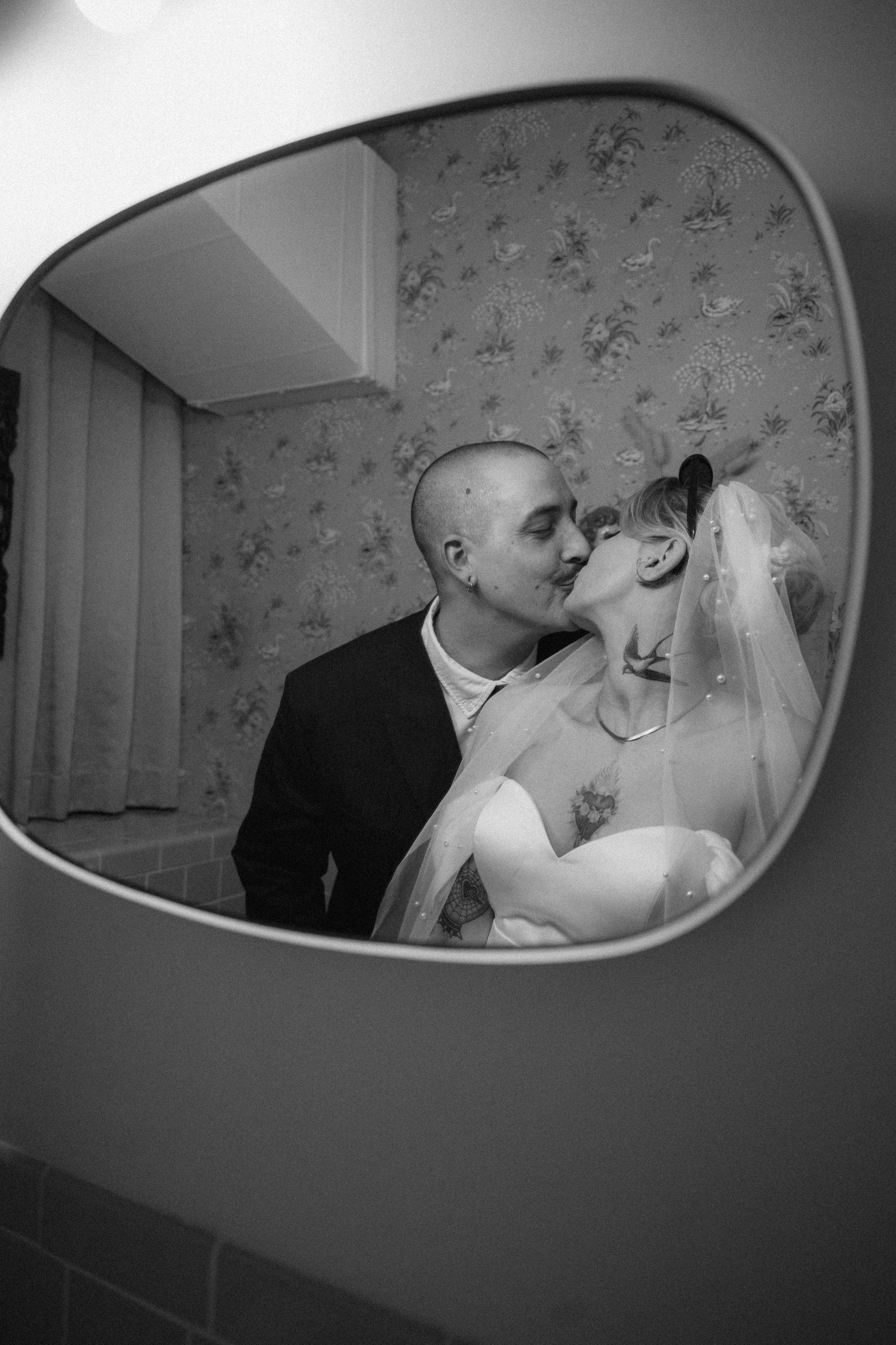An artistic black and white mirror reflection captures an intimate wedding moment.