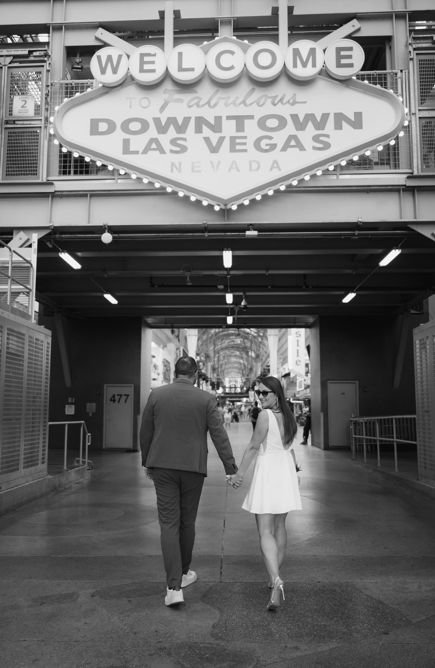 A couple walks through the iconic Downtown Las Vegas welcome sign entrance.