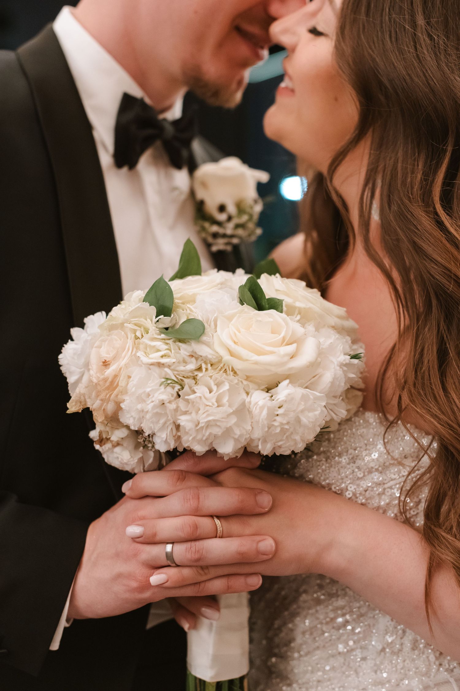 Romantic moment with white rose bouquet between couple at wedding celebration.