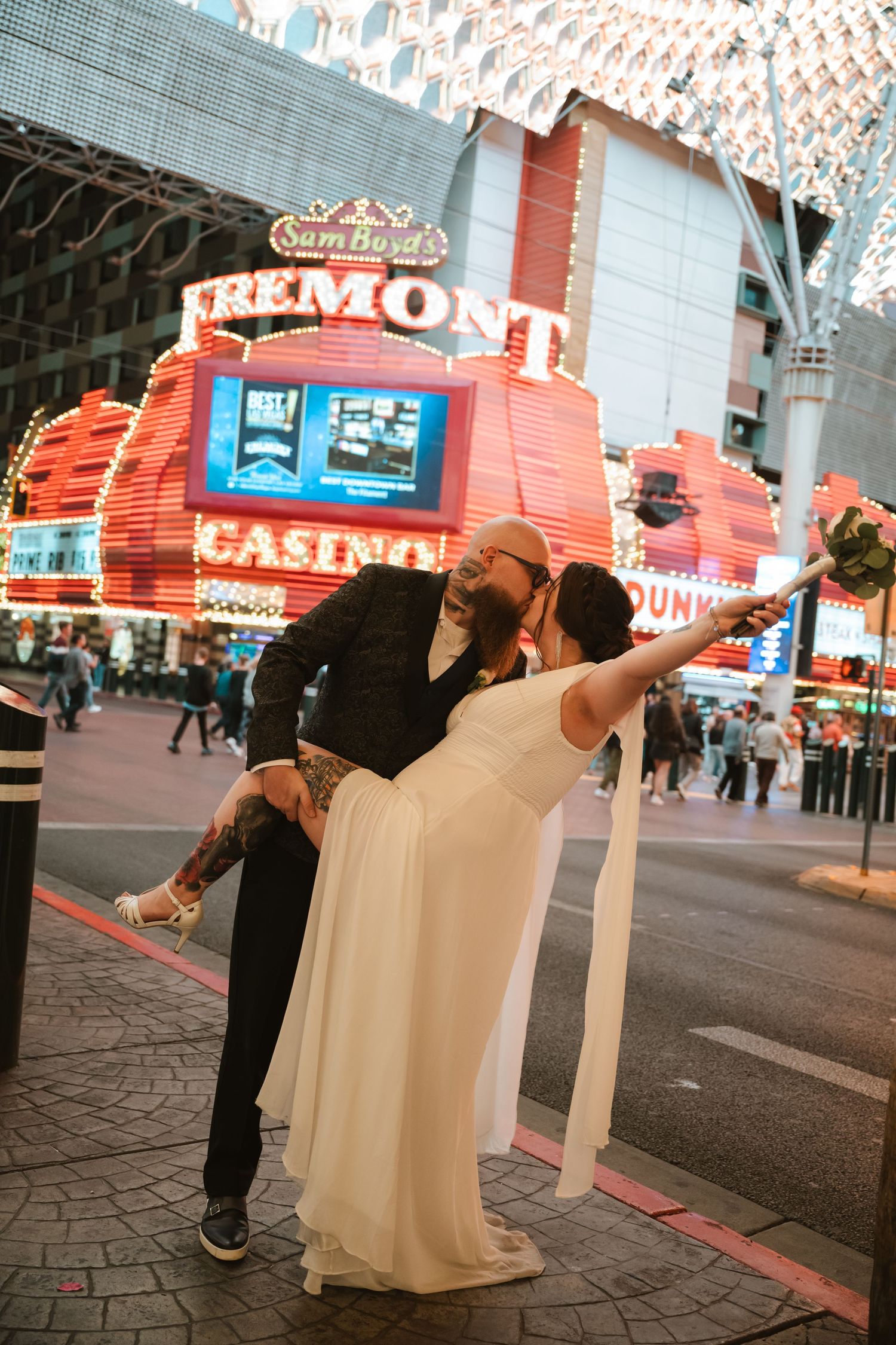 A romantic couple dancing and dipping in front of the illuminated Fremont Casino in downtown Las Vegas.