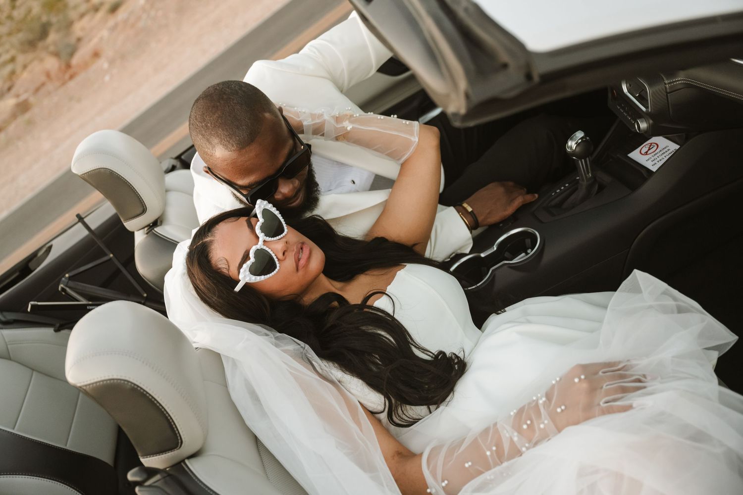 Candid wedding car photos capturing tender moments between newlyweds in black and white.