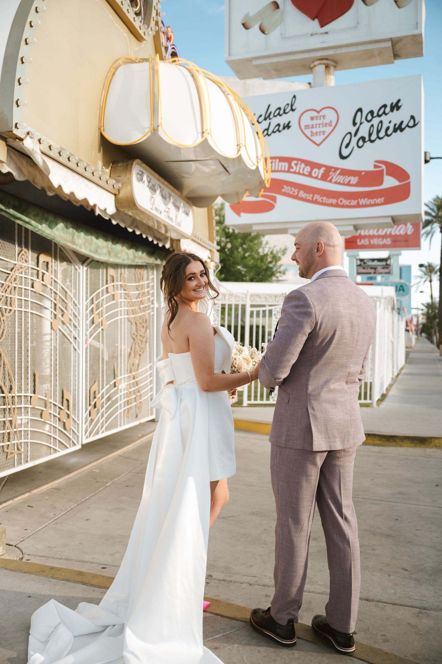 Wedding couple poses outside a retro Las Vegas chapel with vintage signage.