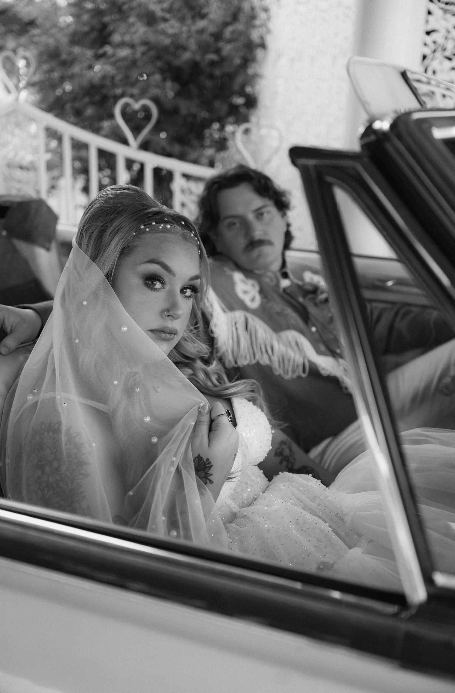 A black and white vintage-style wedding photo taken through a car window.
