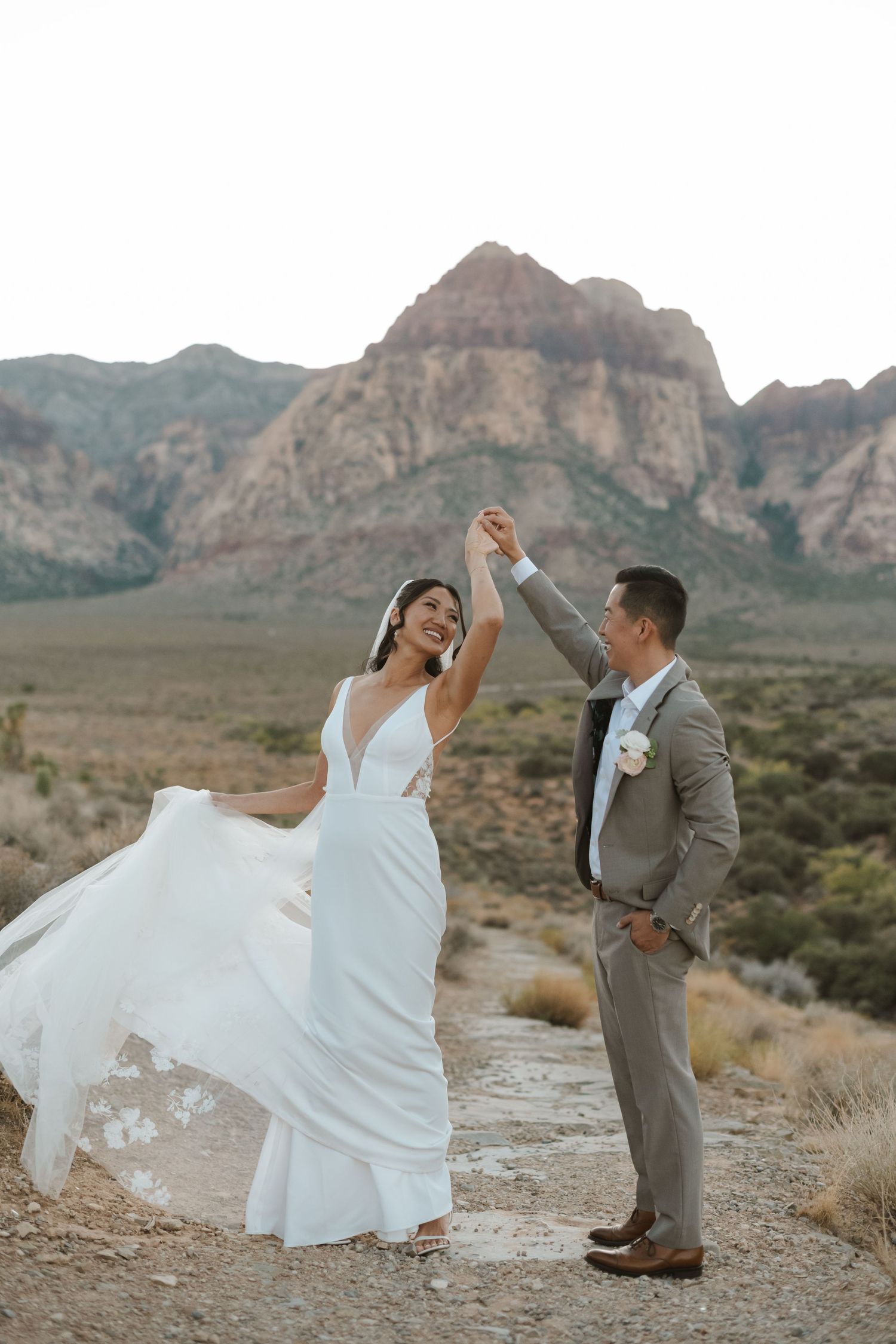 Bride and groom dancing outdoors at Red Rock Canyon, Nevada, with stunning mountain backdrop on their wedding day.