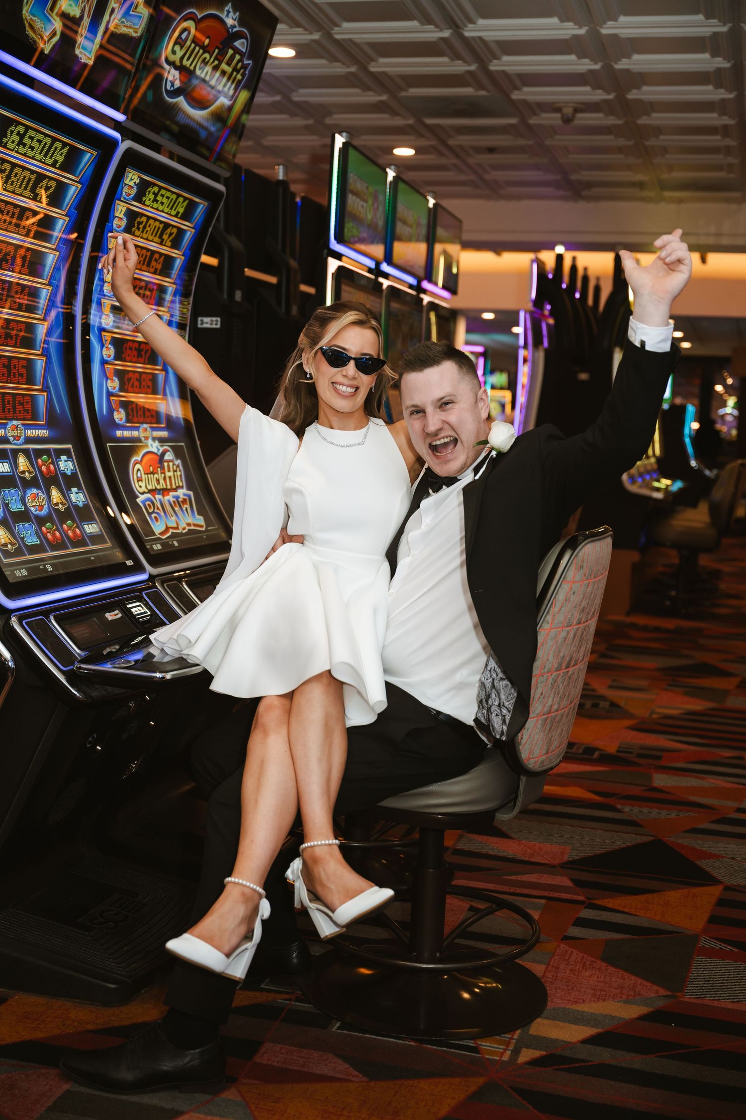 Wedding couple having fun taking photos in a casino with slot machines in the background.