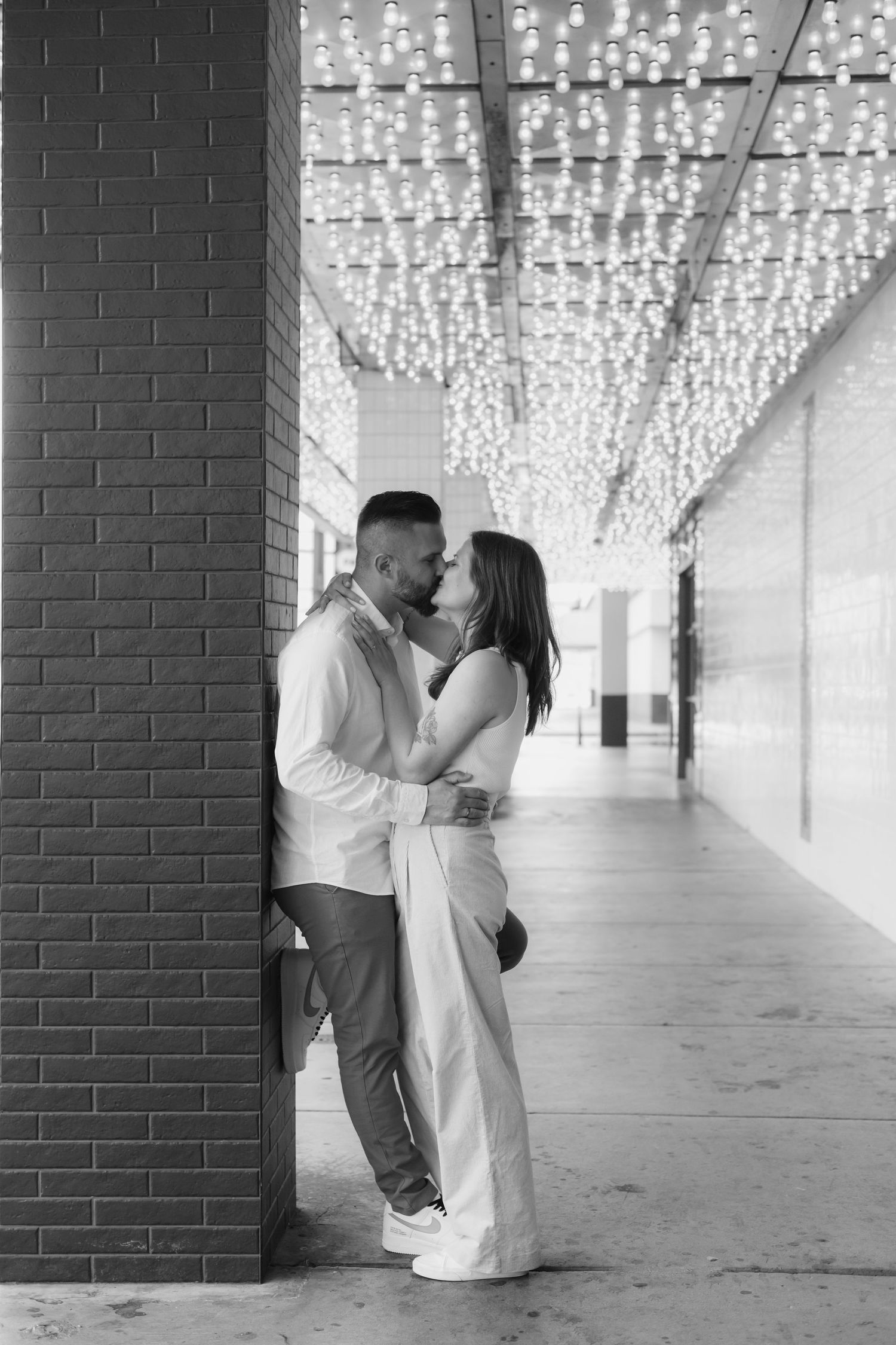 Romantic portraits under a ceiling of twinkling fairy lights in an urban setting.