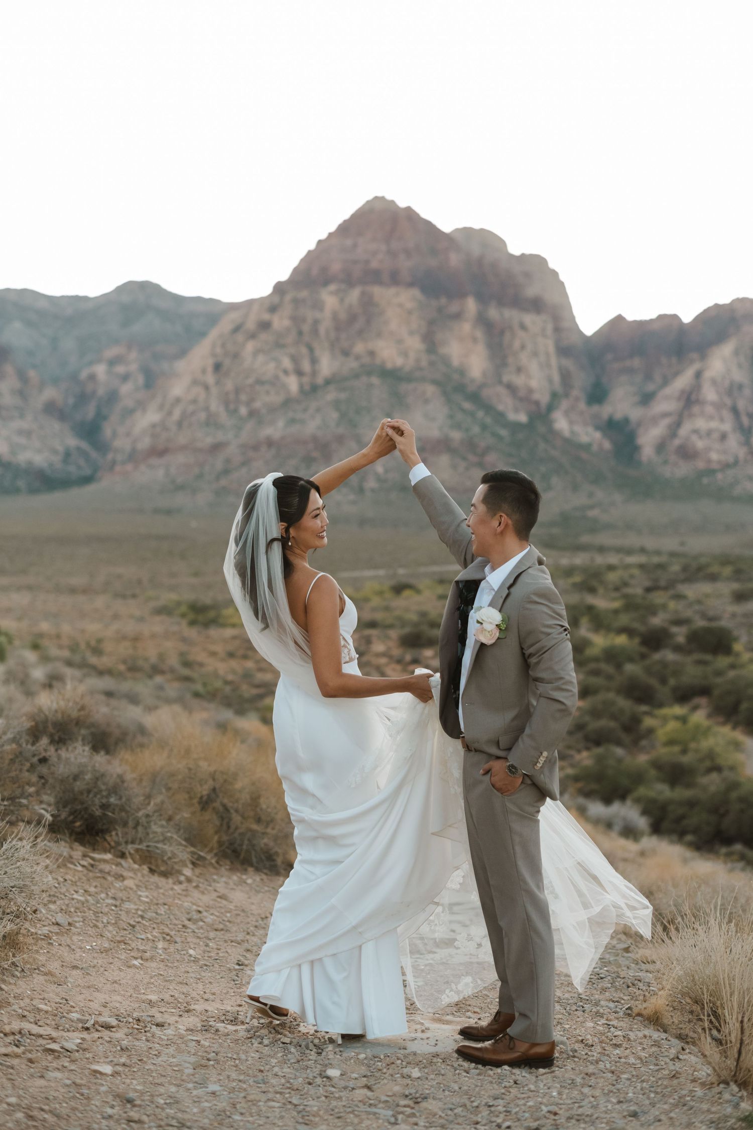 A bride and groom dance together at Red Rock Canyon, Nevada, with stunning desert mountains in the background.