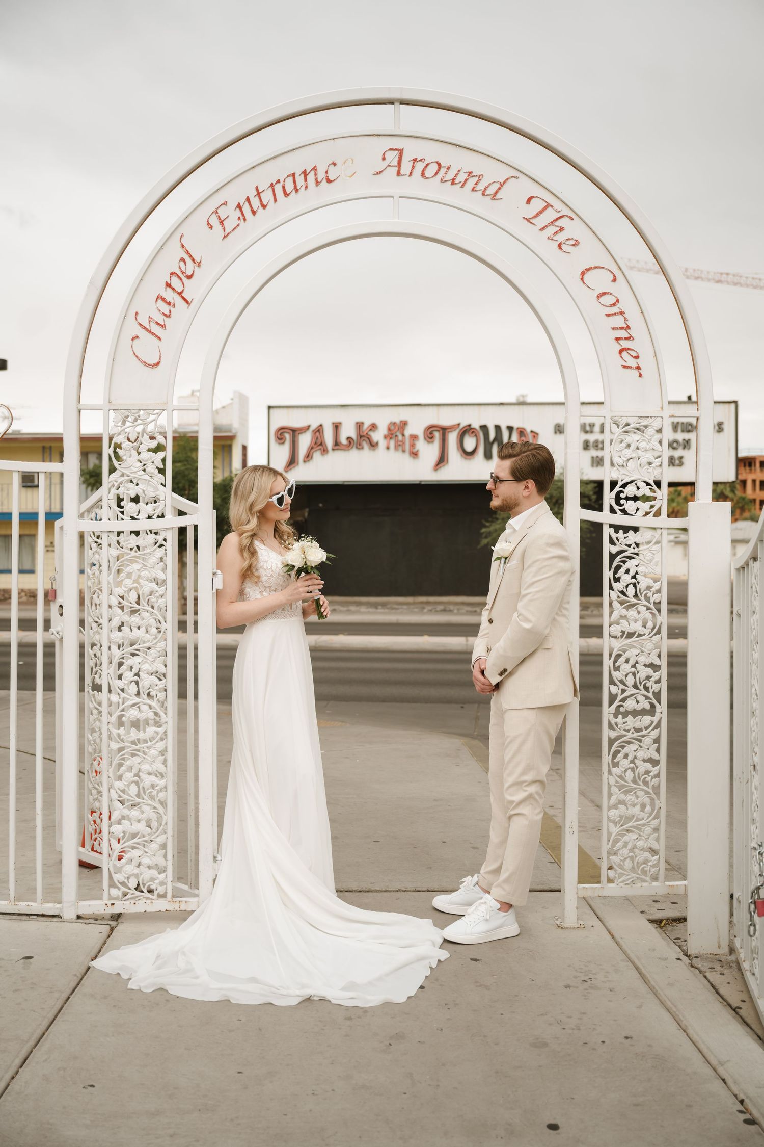 Wedding photos taken under decorative white arches with text on a sunny day.