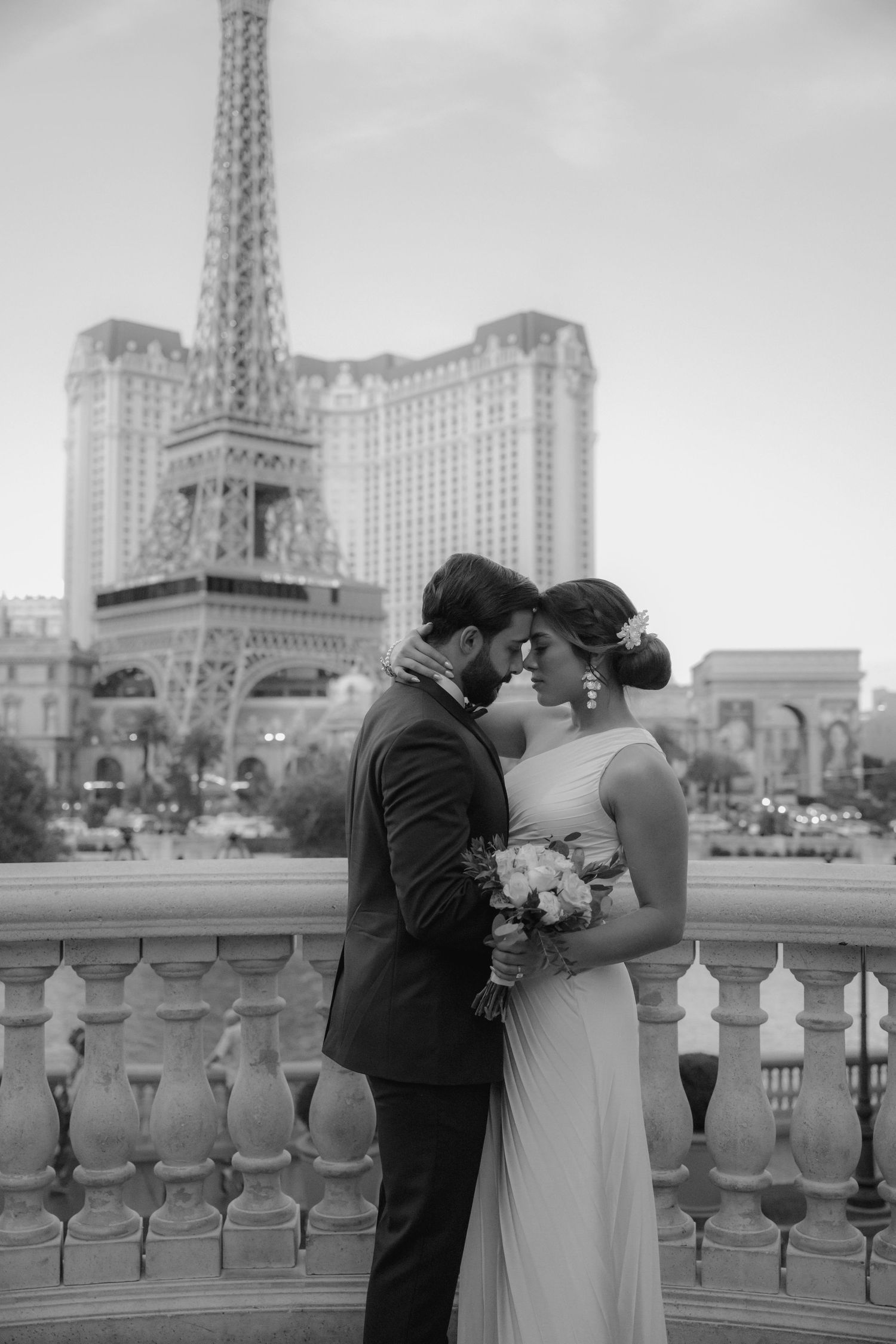 A romantic wedding moment captured in black and white with the Paris Las Vegas hotel and Eiffel Tower replica in view.