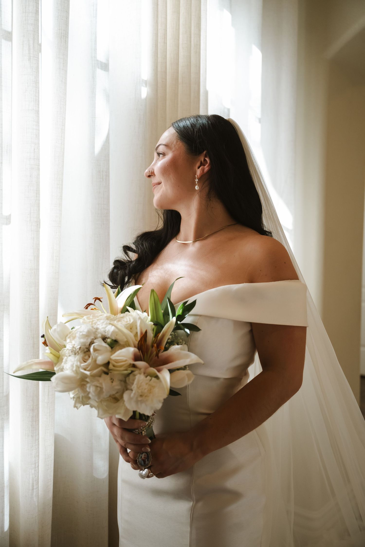 An elegant bridal portrait series featuring a white wedding gown and bouquet of roses near sheer curtains.
