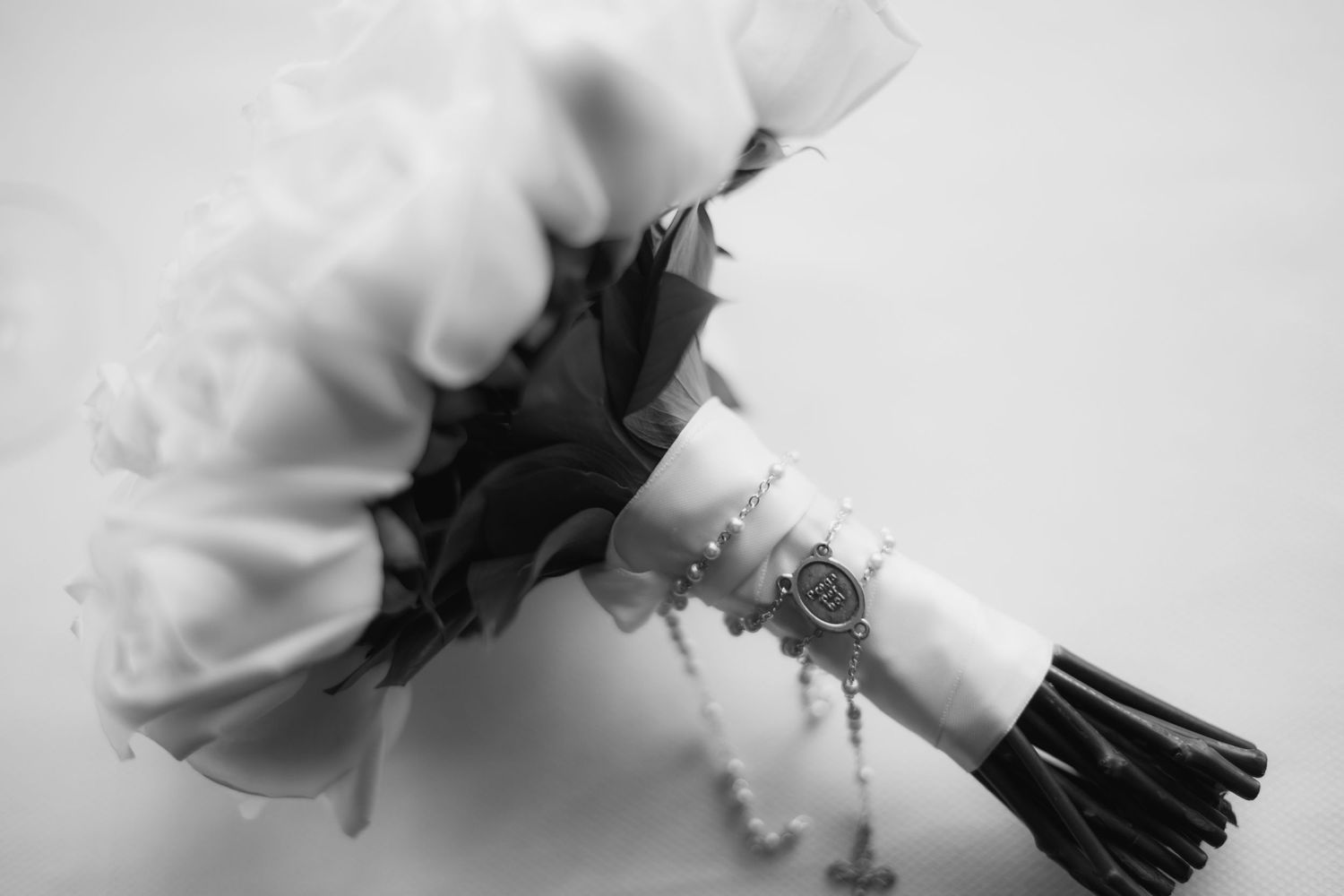 Black and white photograph of an elegant bridal bouquet wrapped with ribbon and tied with string.