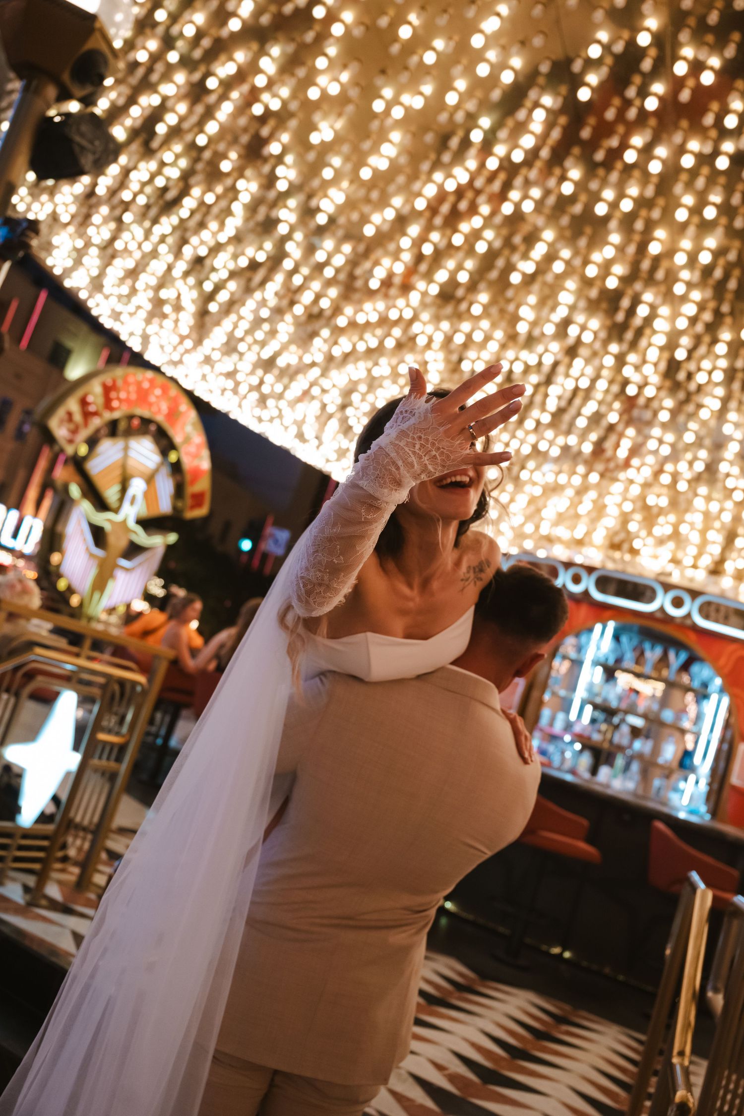 Bride in white dress and lace gloves dancing under sparkling lights at a Las Vegas wedding venue.