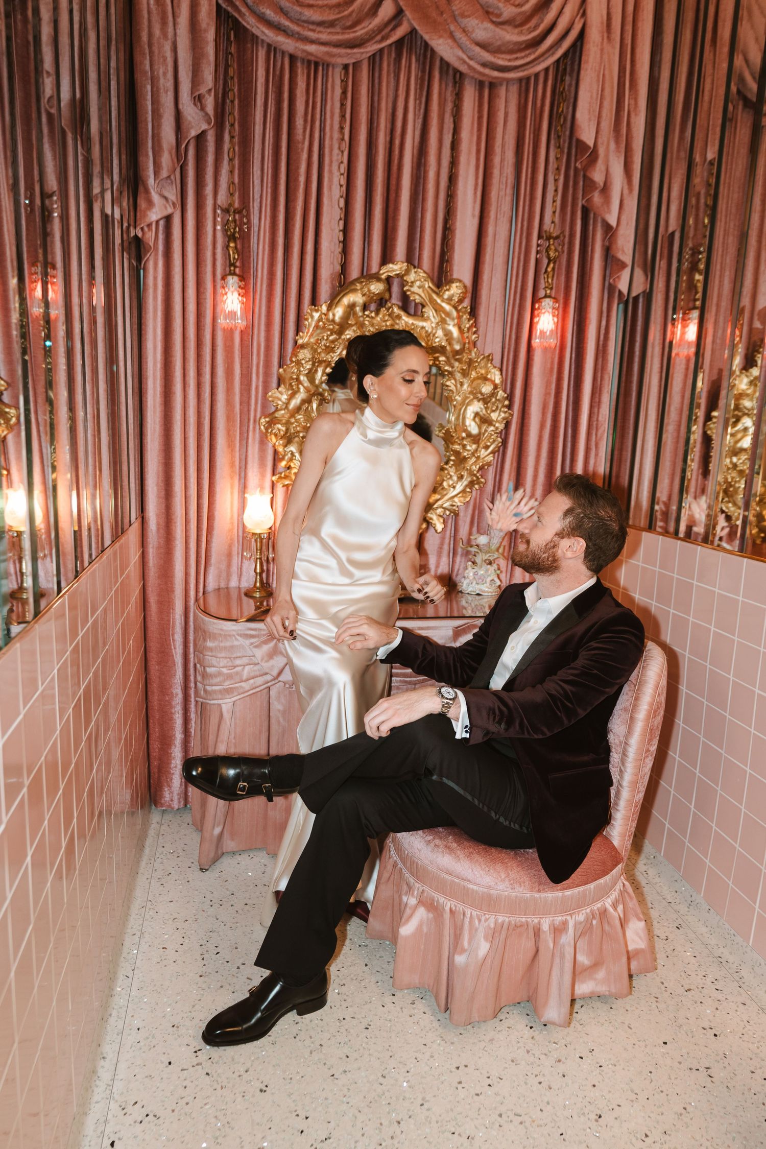 A playful wedding photo series against pink draped curtains with gold accents.