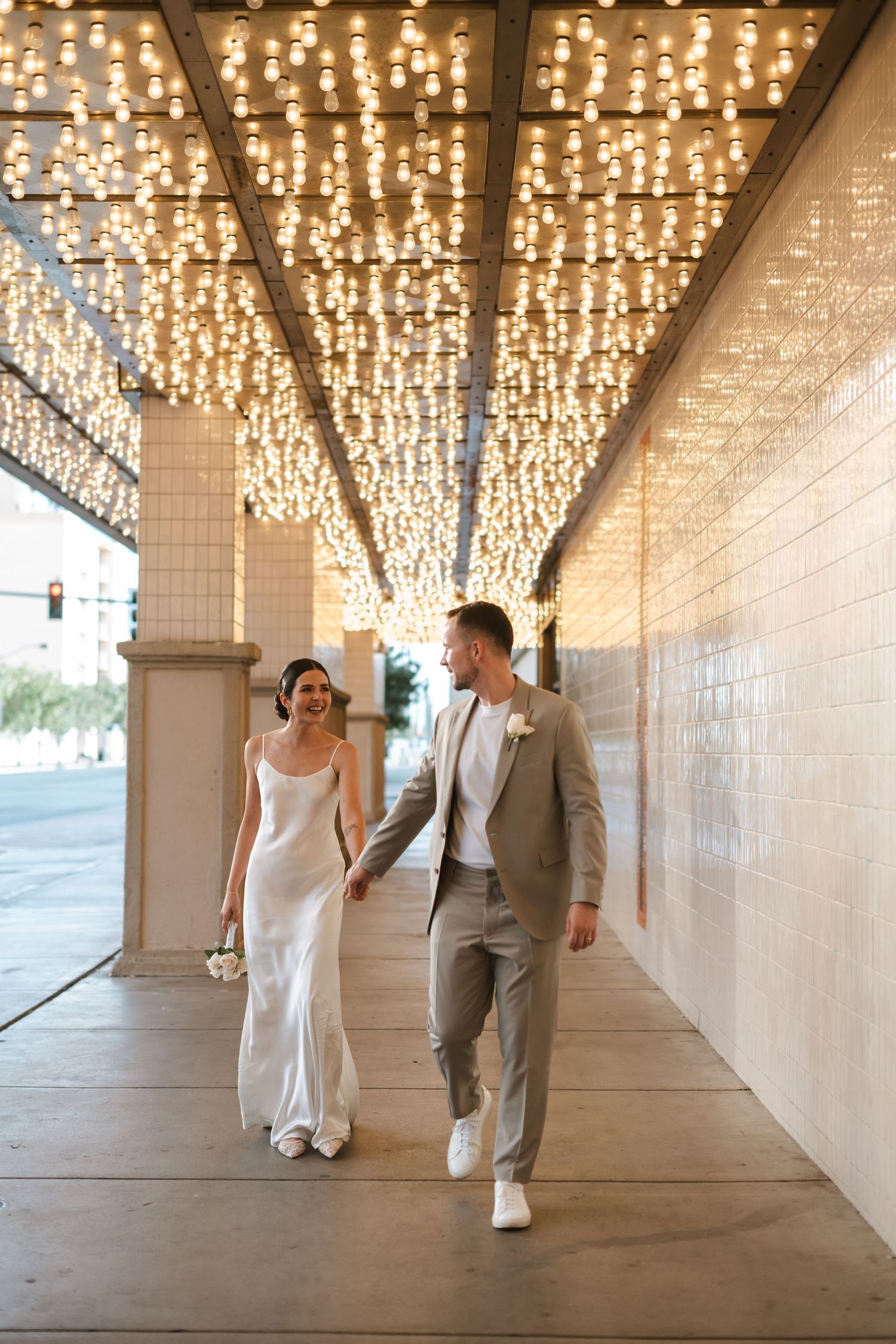 Couple walking through an elegant tunnel with a stunning ceiling of twinkling string lights creating a magical atmosphere.