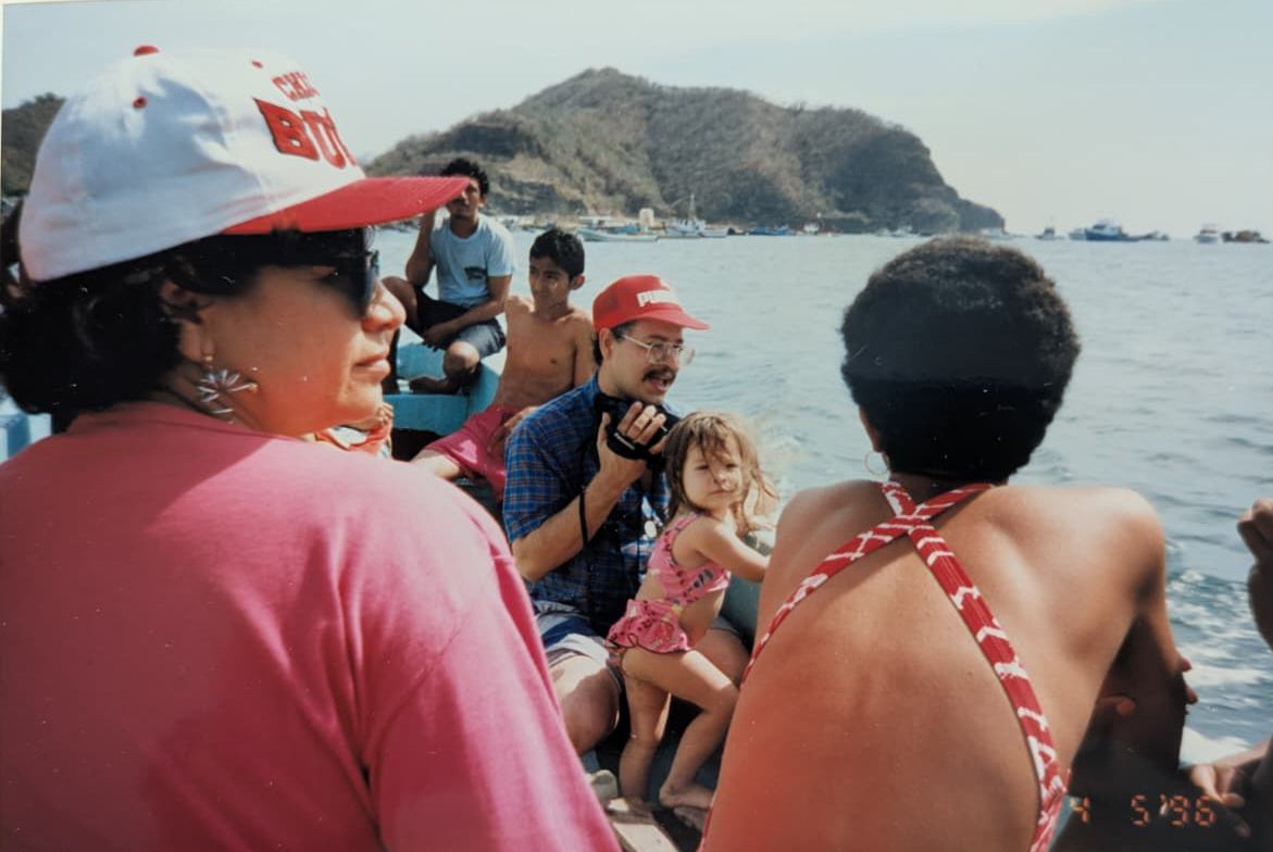 People enjoying a boat ride along a scenic coastline with mountains visible in the distance.