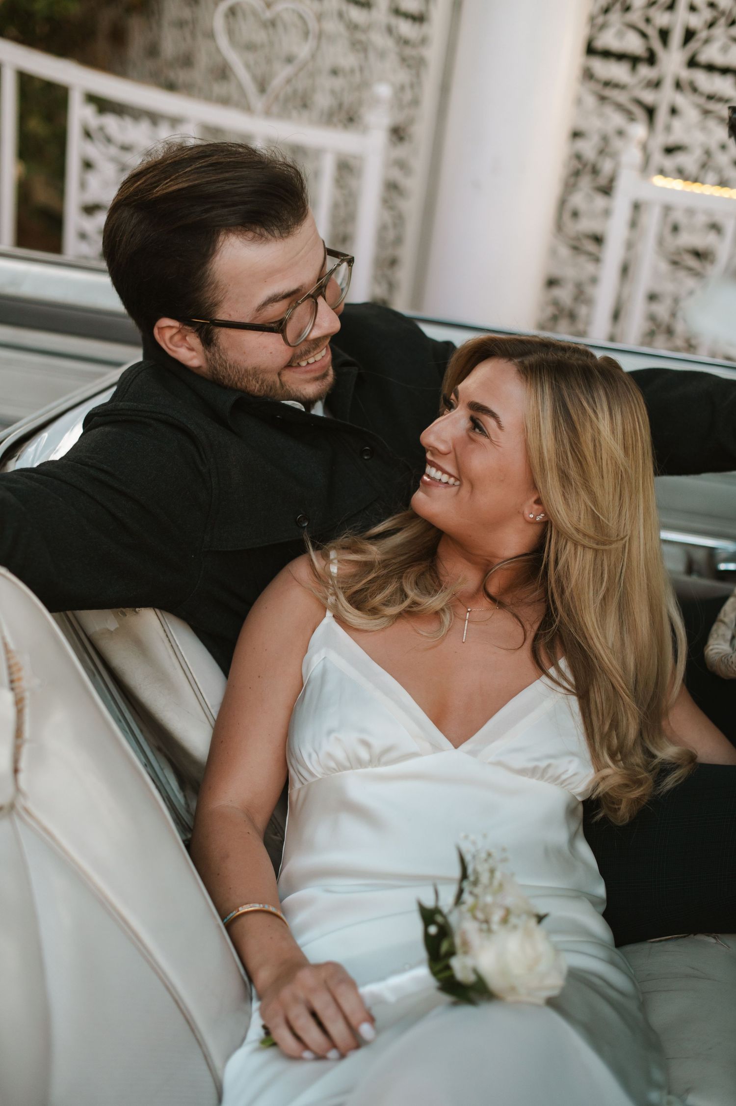 A romantic moment captured between newlyweds on vintage seating.